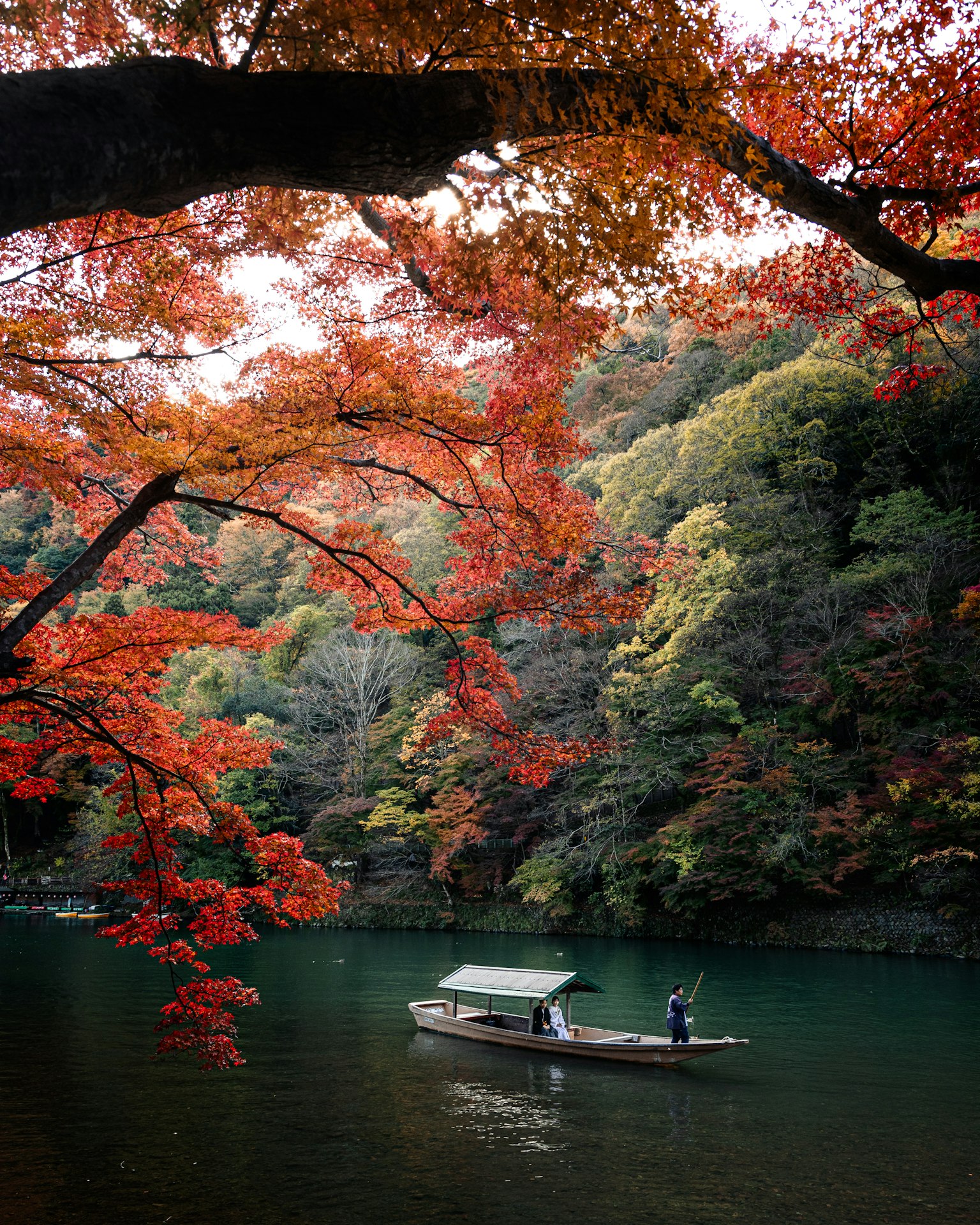 A small boat on a serene water surface surrounded by vibrant autumn foliage