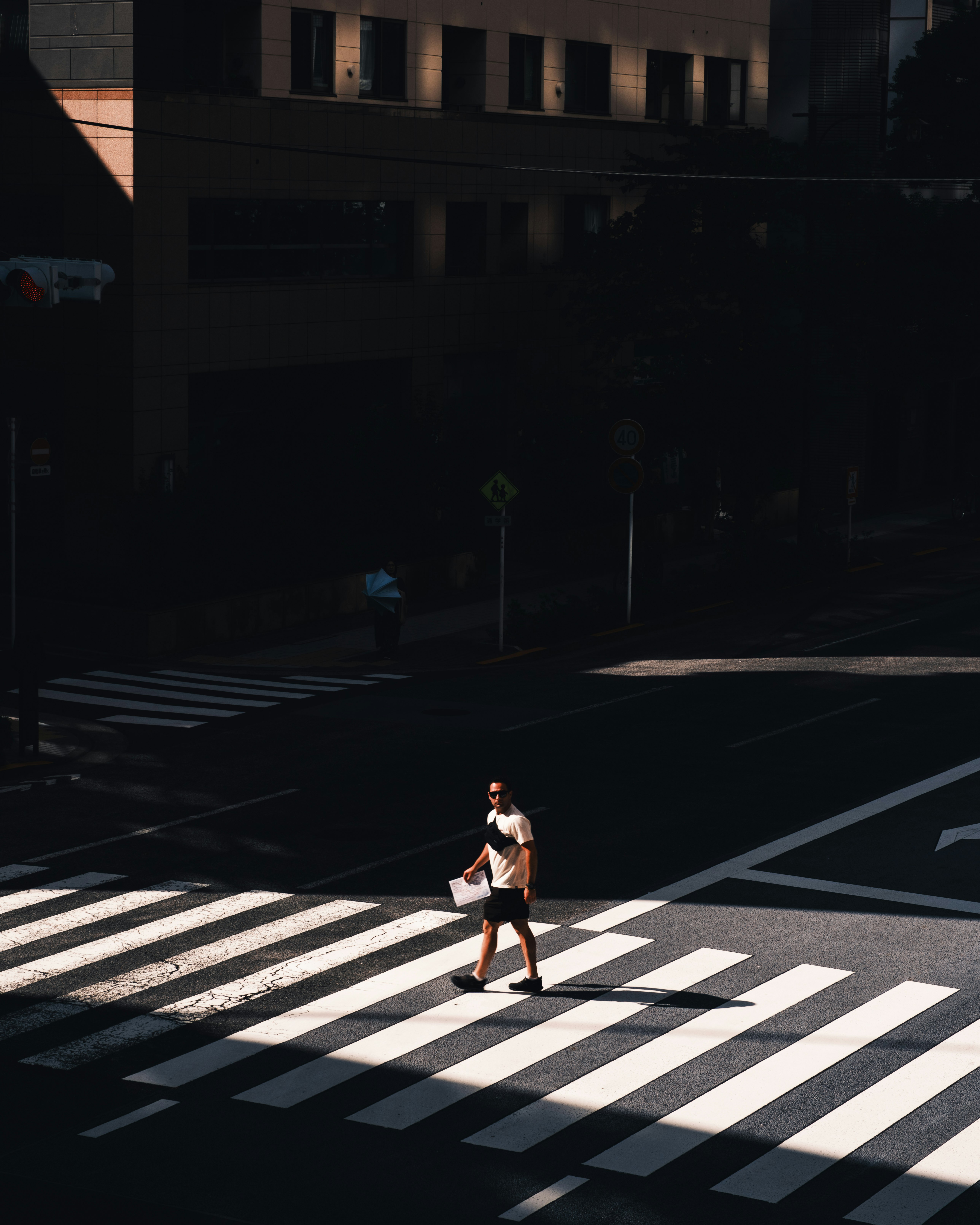 A person walking across a zebra crossing in strong shadows