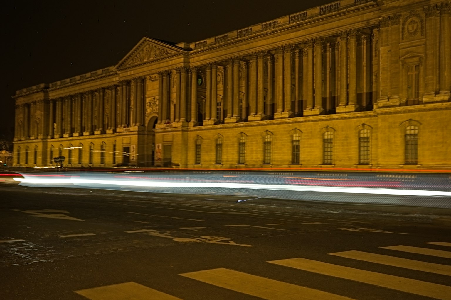 Bâtiment historique illuminé la nuit avec des traînées lumineuses de voitures