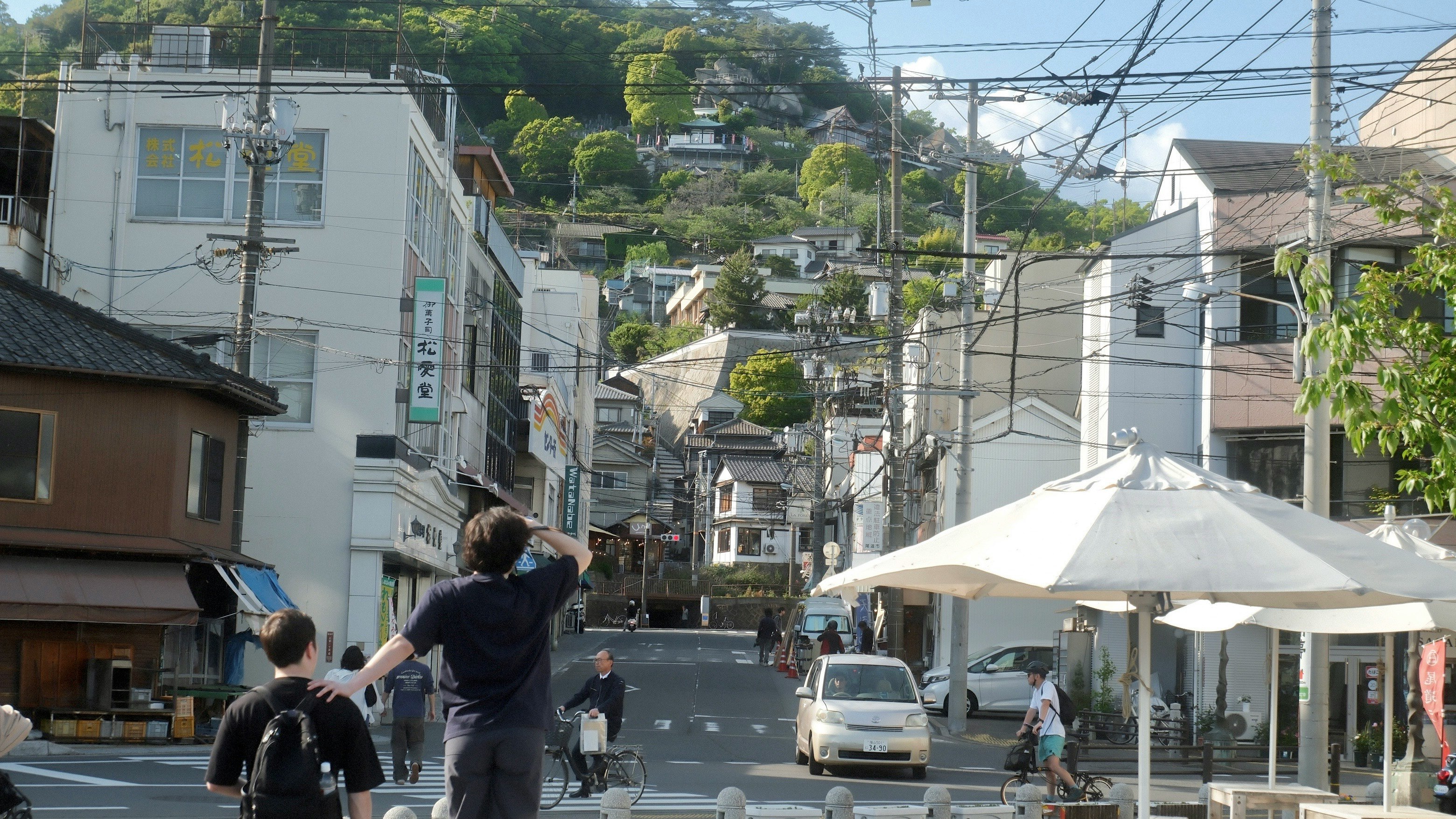 坂道の商店街で屋台テントと自転車が並ぶ街並み