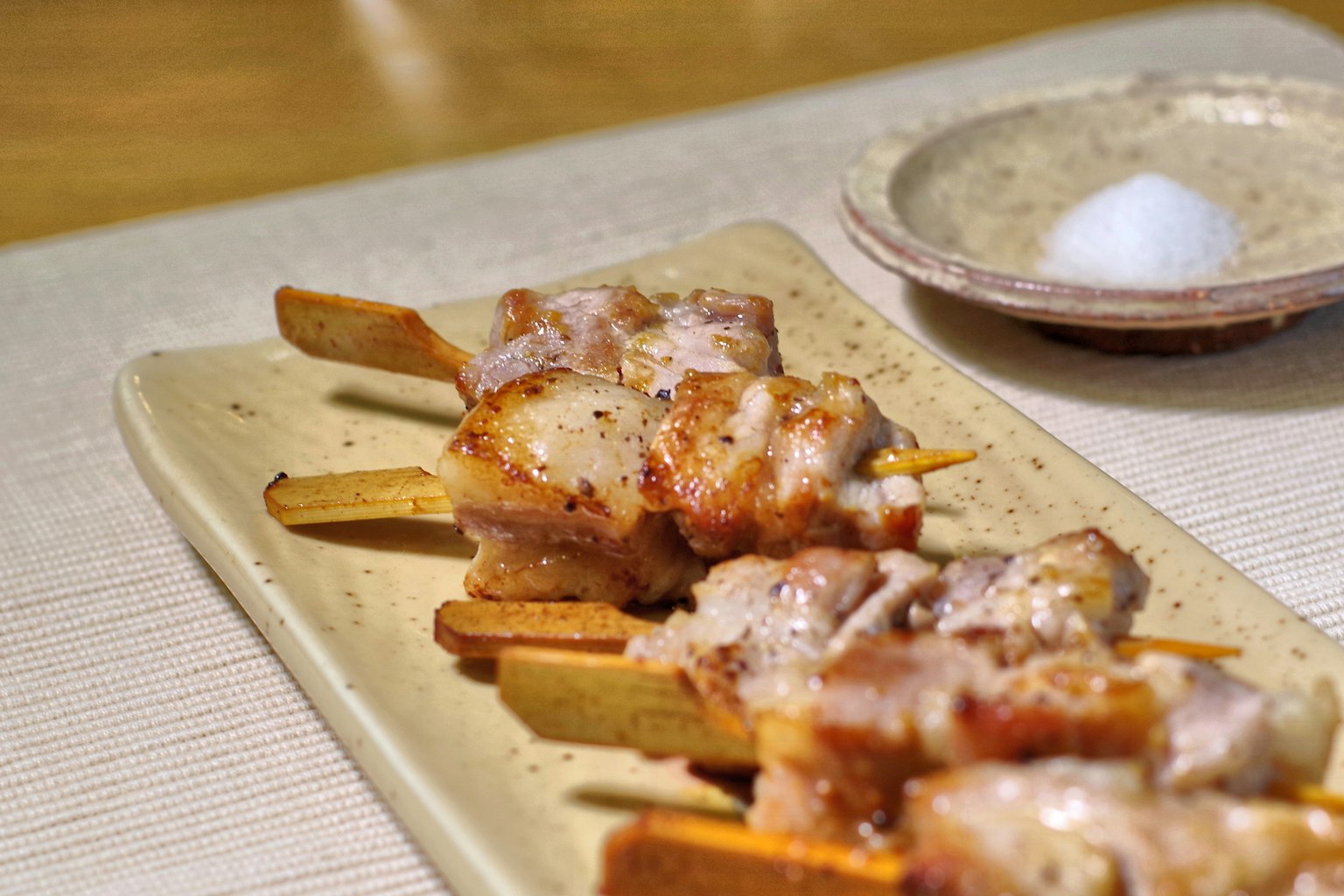 Spiedini di pollo grigliati su un piatto con un piccolo piatto di sale