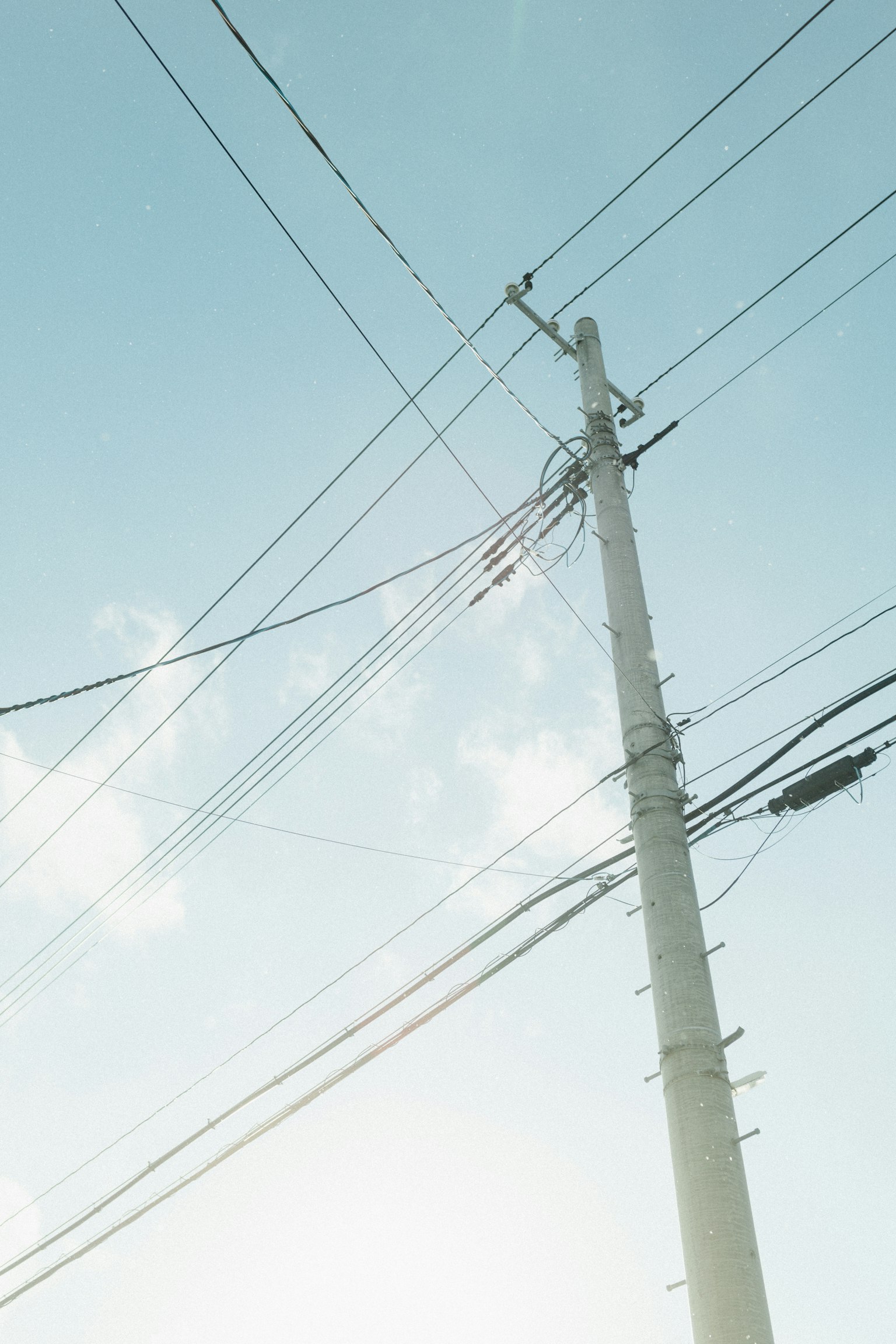 Un poste de luz con cables bajo un cielo azul claro