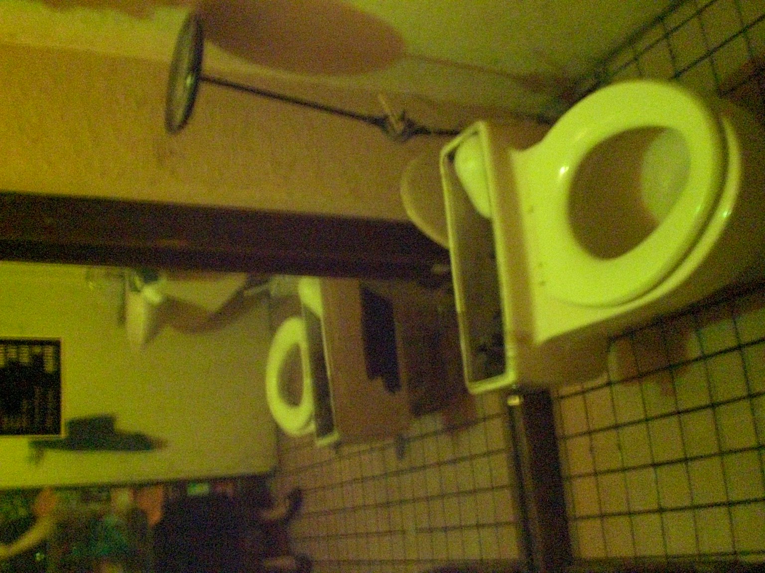 Interior kamar mandi dengan toilet putih dan cermin di dinding kuning