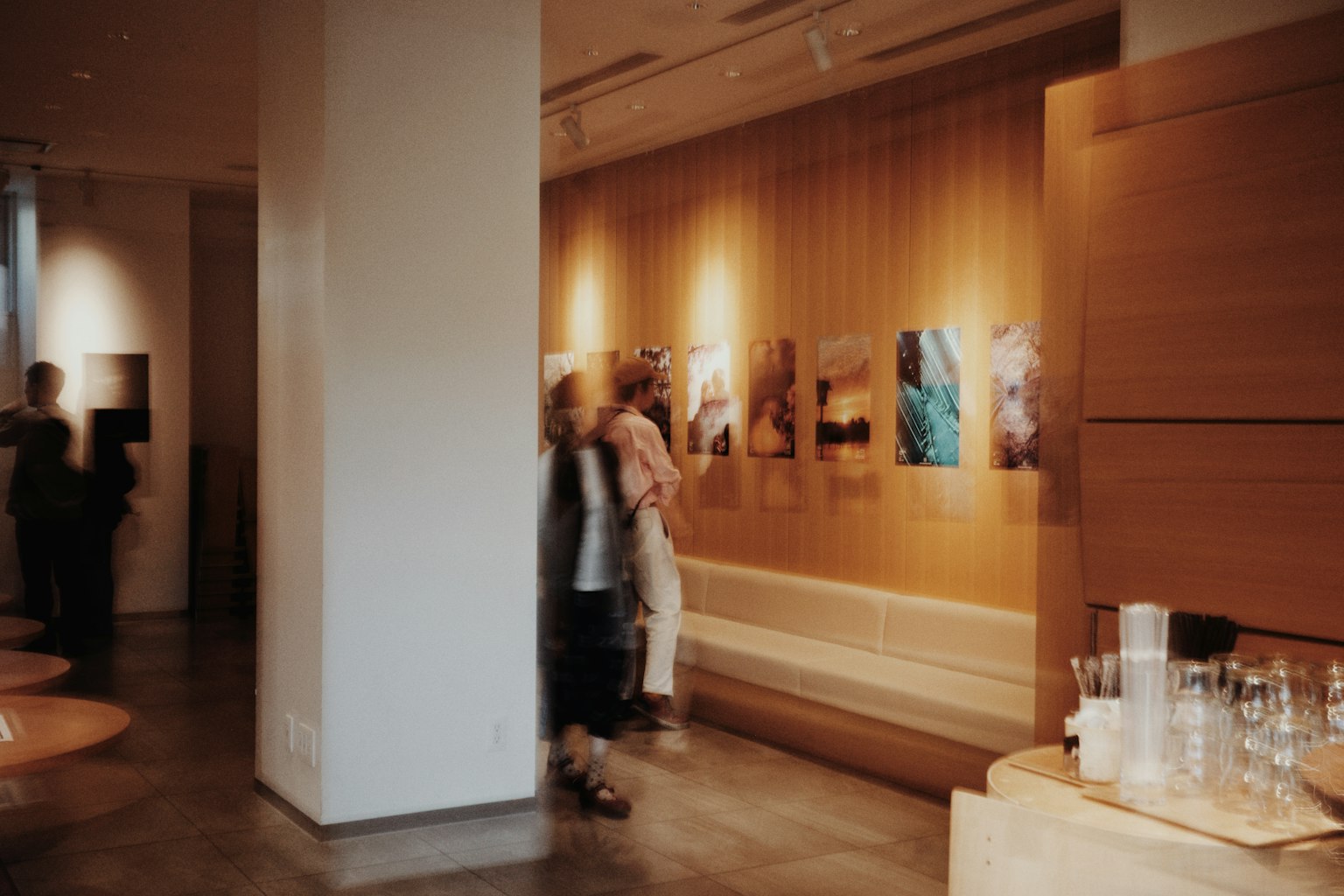 ภายในหอศิลป์สมัยใหม่มีผู้คนชมภาพถ่ายผนังไม้และพื้นที่นั่ง