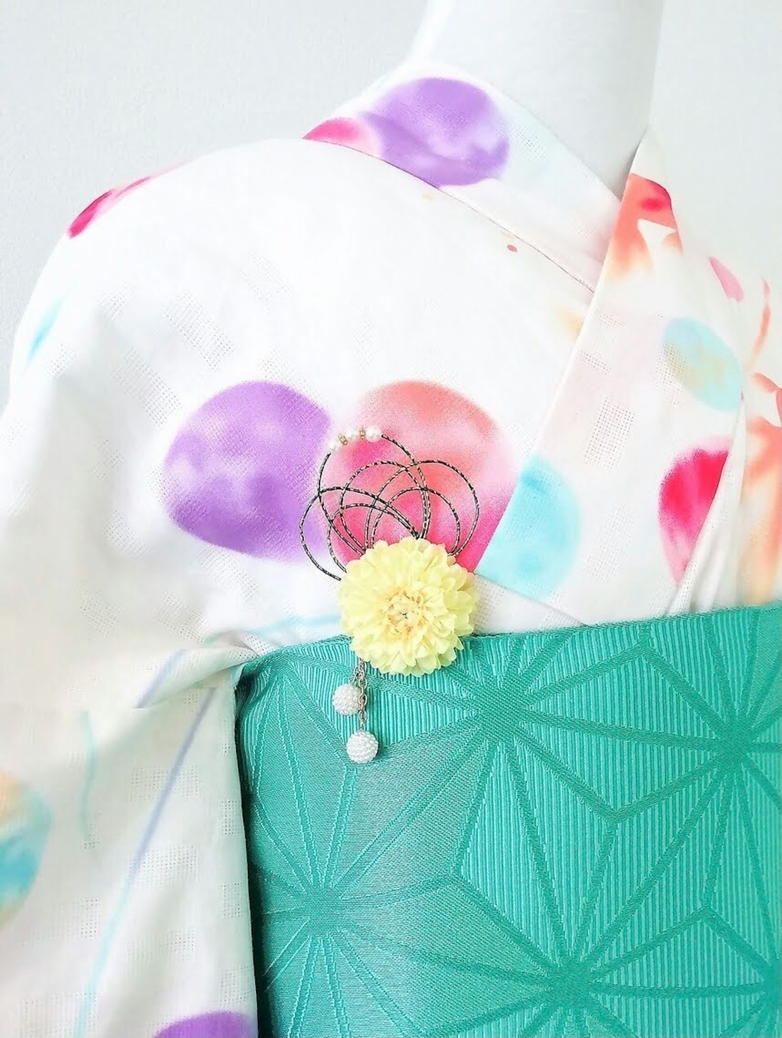 Kimono dengan polkadot berwarna di latar belakang putih dan obi hijau dengan pola geometris