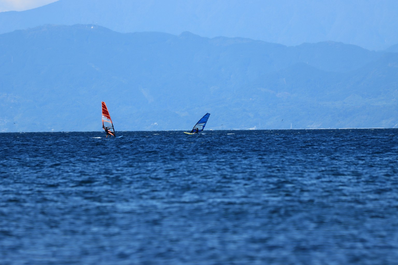 Dos tablas de viento deslizándose sobre un mar azul