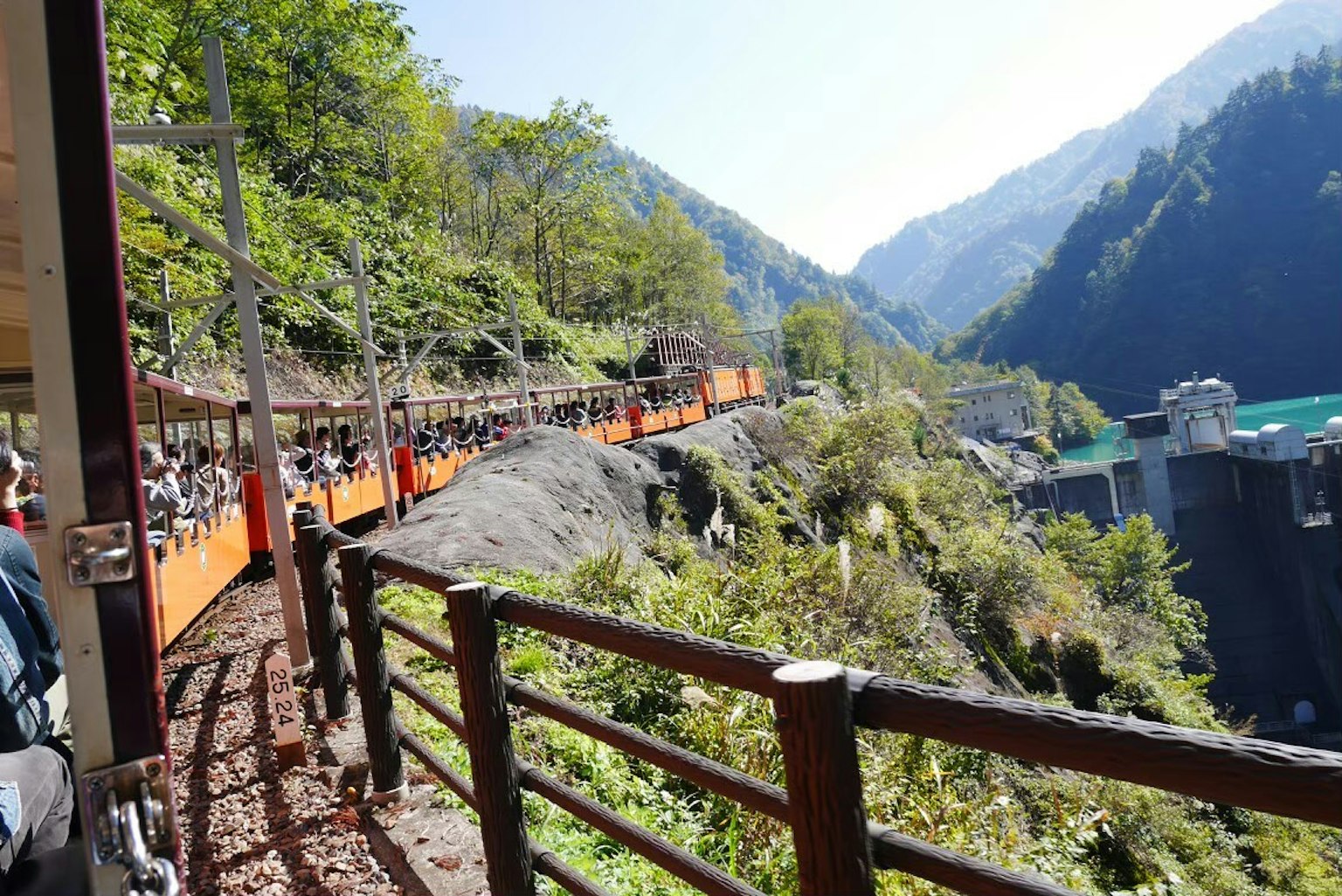 Scenic view of a dam with a walkway surrounded by mountains and greenery