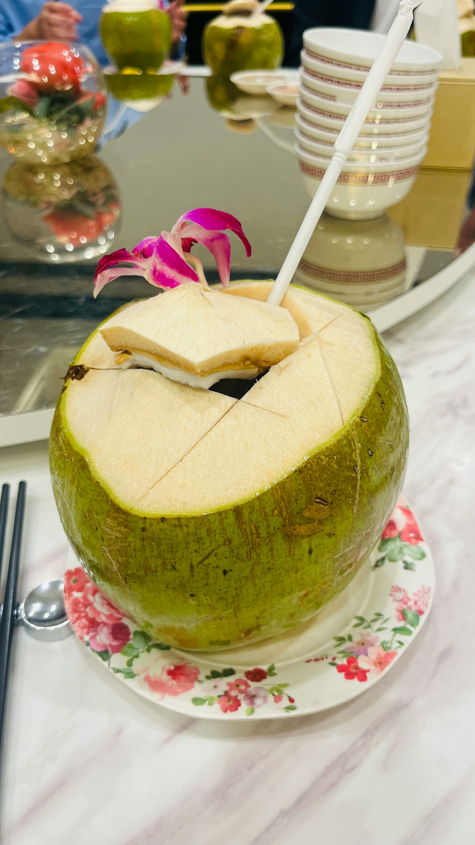 Cocco verde con una cannuccia e una decorazione floreale