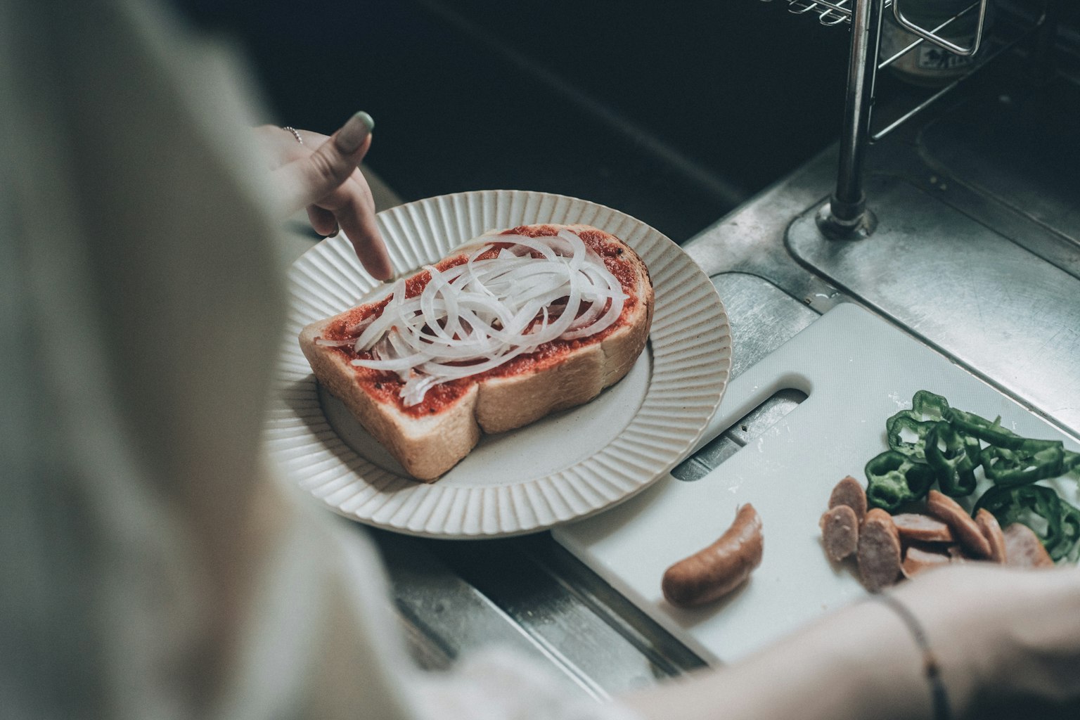 Một người phụ nữ đang chuẩn bị bánh mì nướng với sốt cà chua và hành tây thái lát