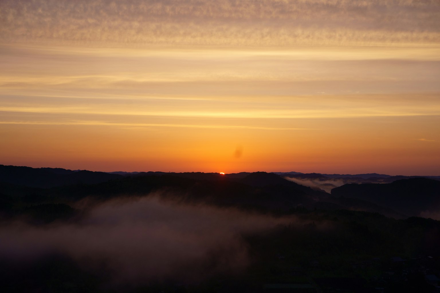 Schöner Sonnenaufgang, der zwischen den Bergen mit sanften Wolken auftaucht