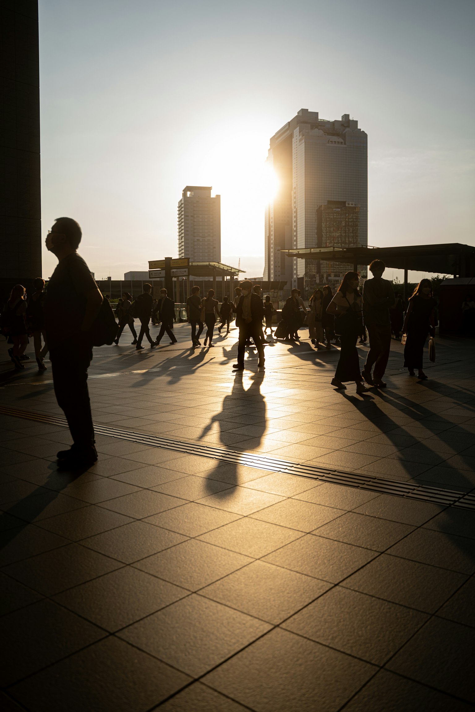 Urban scene with people walking against a sunset backdrop
