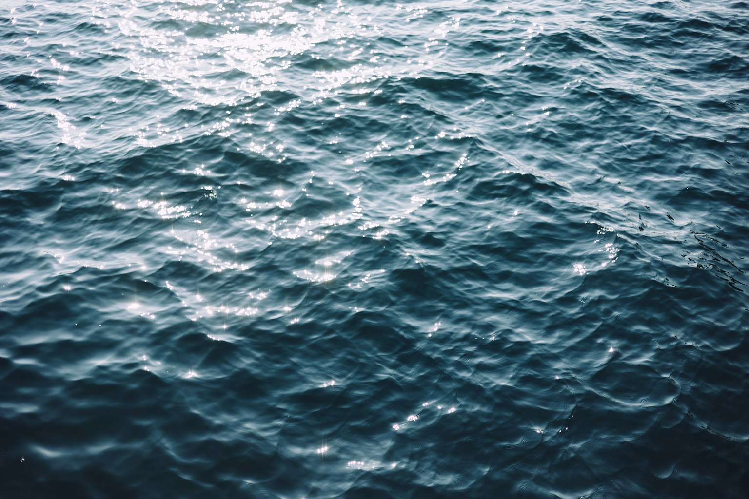 Superficie dell'oceano blu increspato che riflette la luce