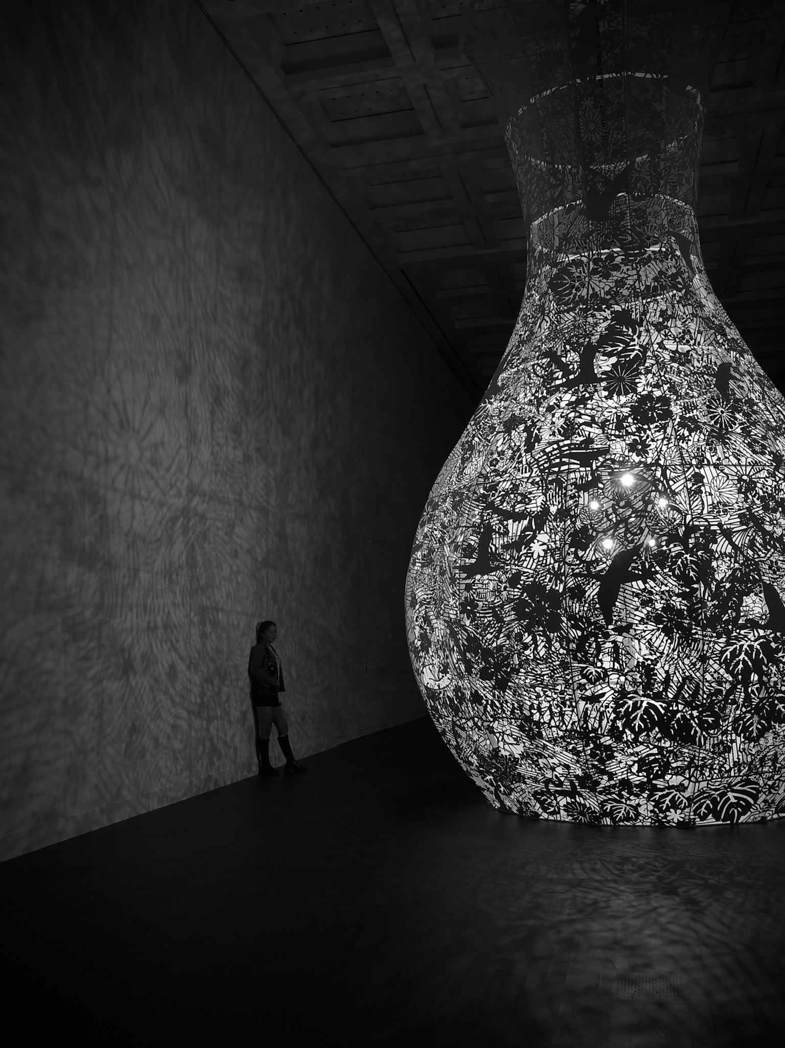 Gran lámpara decorativa en una habitación oscura con la silueta de una persona