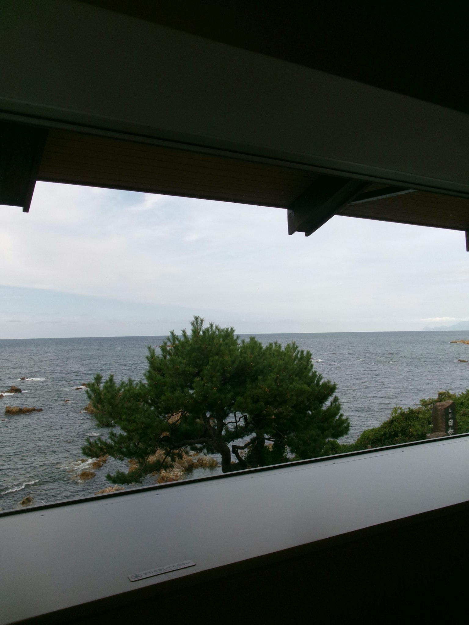 海の景色を見渡す窓からの眺め 緑の木と岩が見える