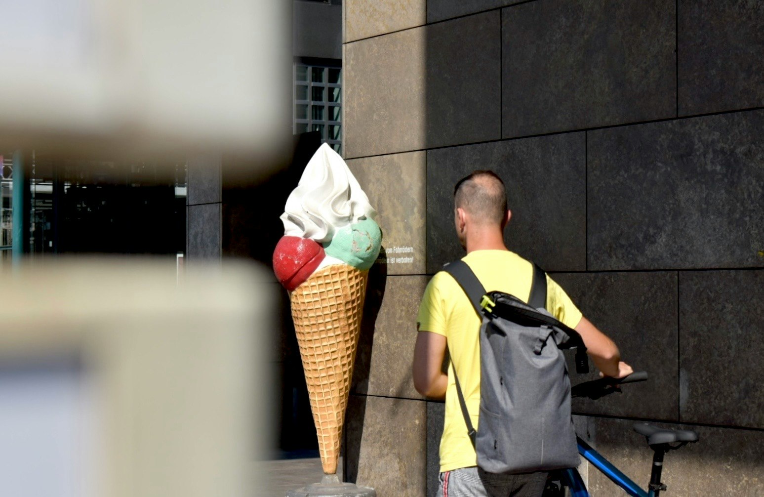 eine Person mit Eiscreme entlang einer Berliner Mauer