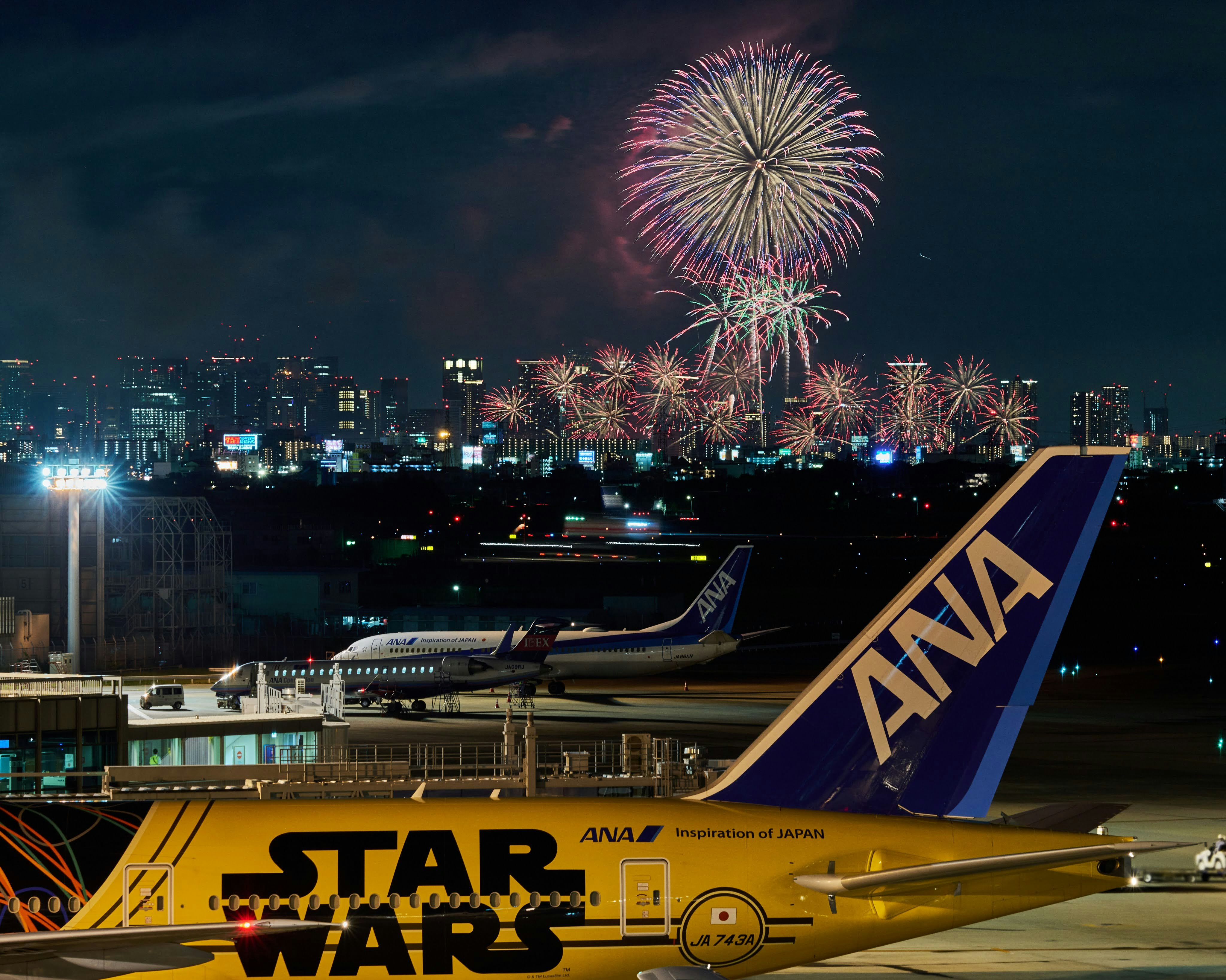 夜の空港でANA機体と打ち上げ花火が見える景色