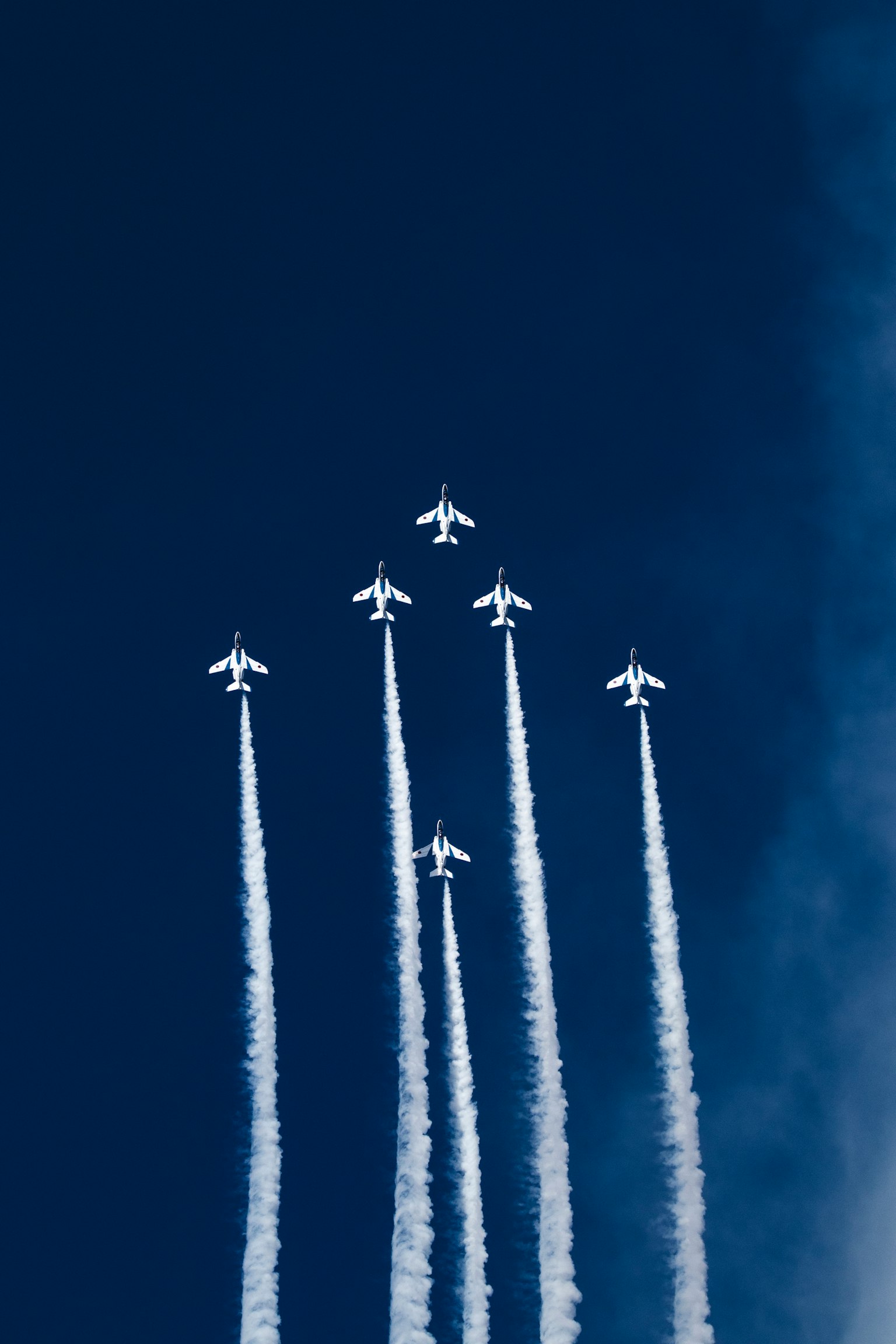 Formación de aviones blancos ascendiendo en un cielo azul