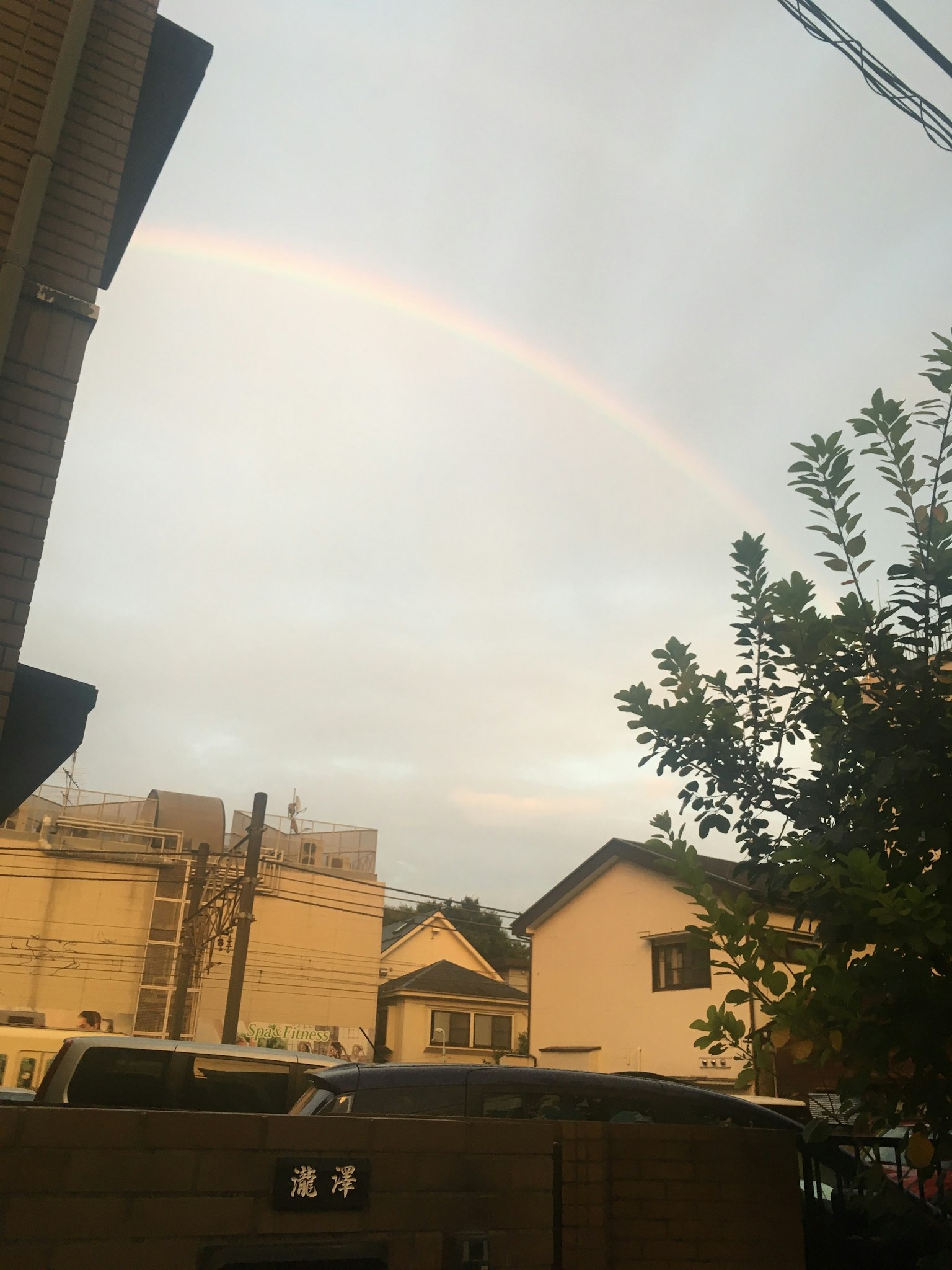 Un arc-en-ciel pâle au-dessus d'un quartier résidentiel avec des bâtiments environnants