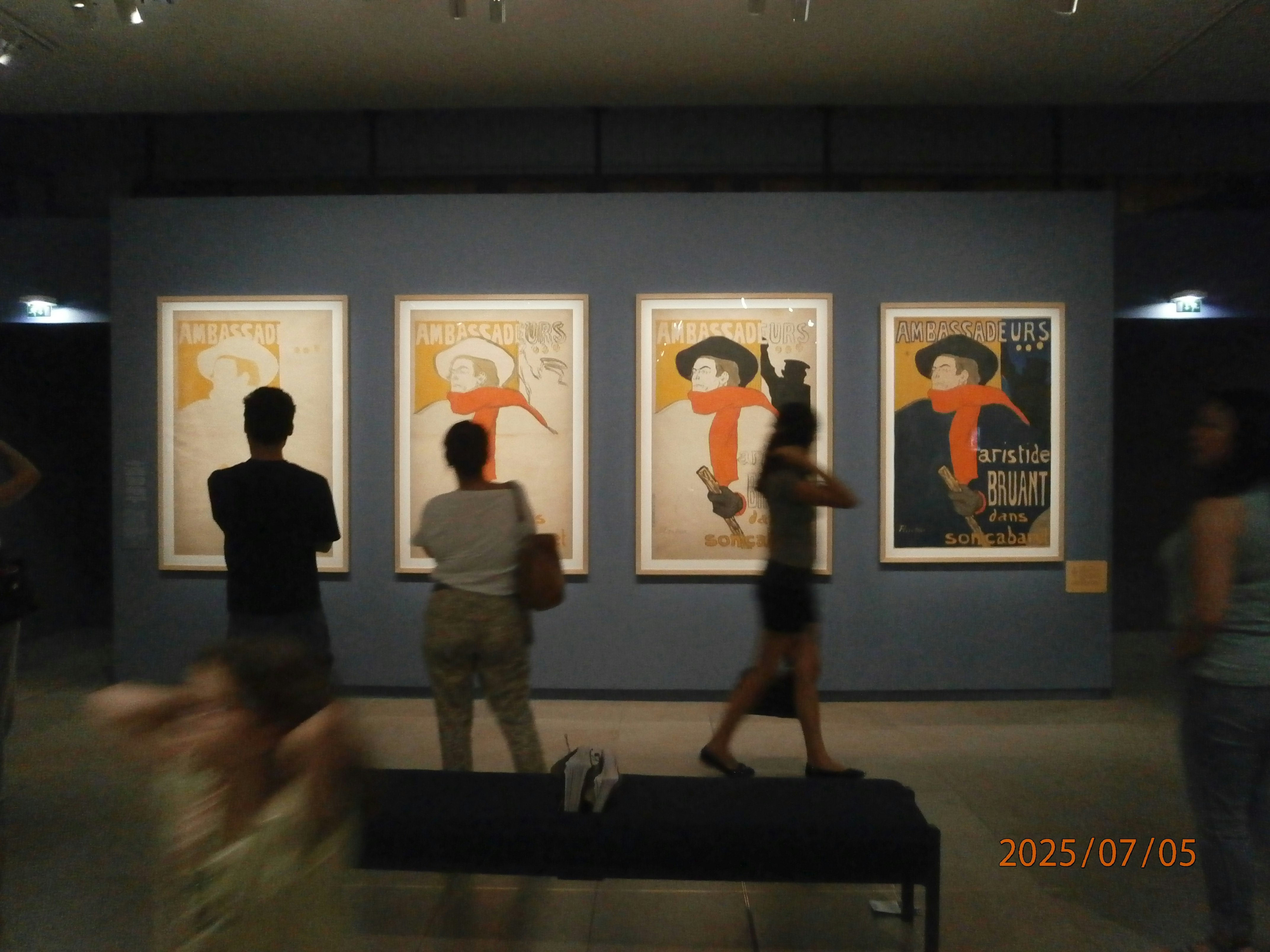 オルセー美術館の壁に並ぶ絵画ポスターを鑑賞する人々のある展示室