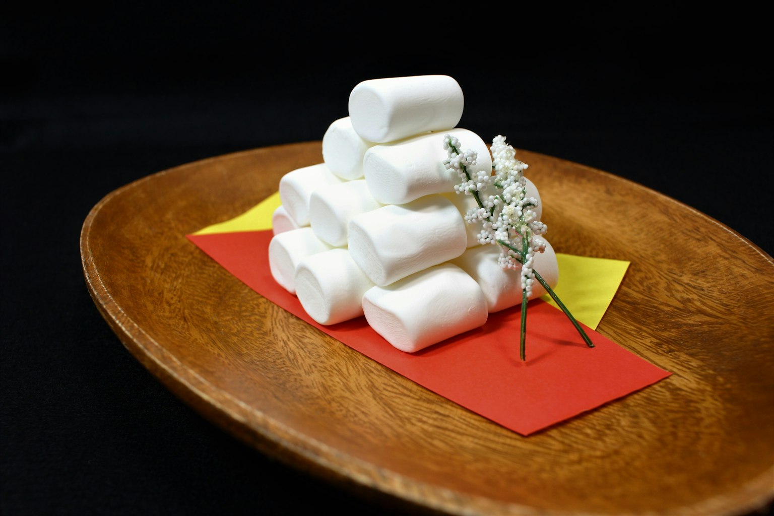 Stack of white marshmallows with a small flower on a wooden plate