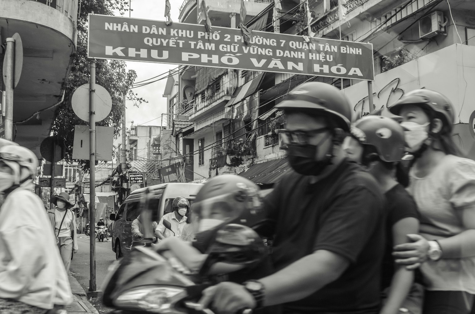 Ein Mann und eine Frau fahren mit dem Motorrad durch die Straße mit einem vietnamesischen Schild im Hintergrund