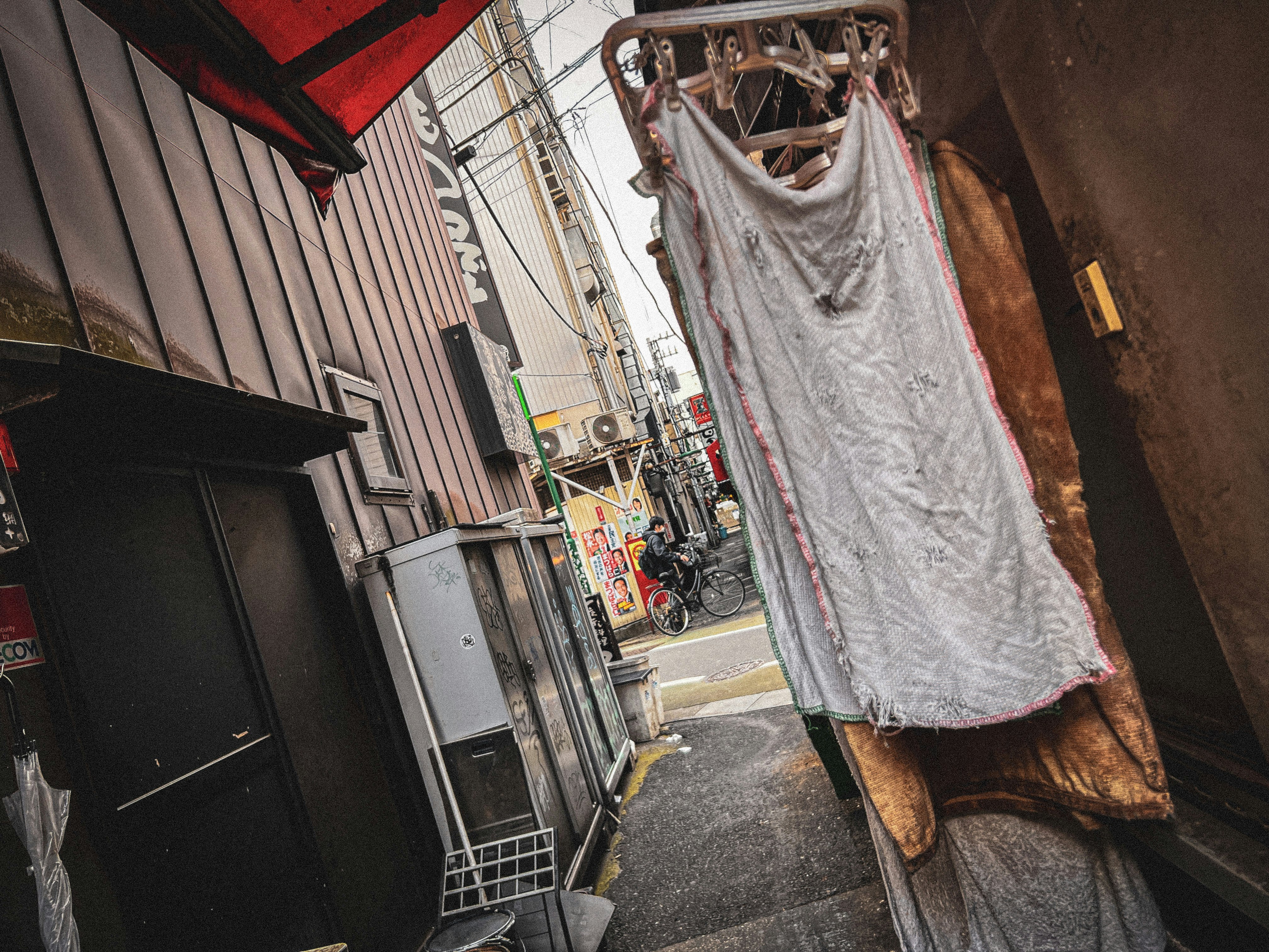 laundry hanging over a narrow Tokyo shopping alley storefront