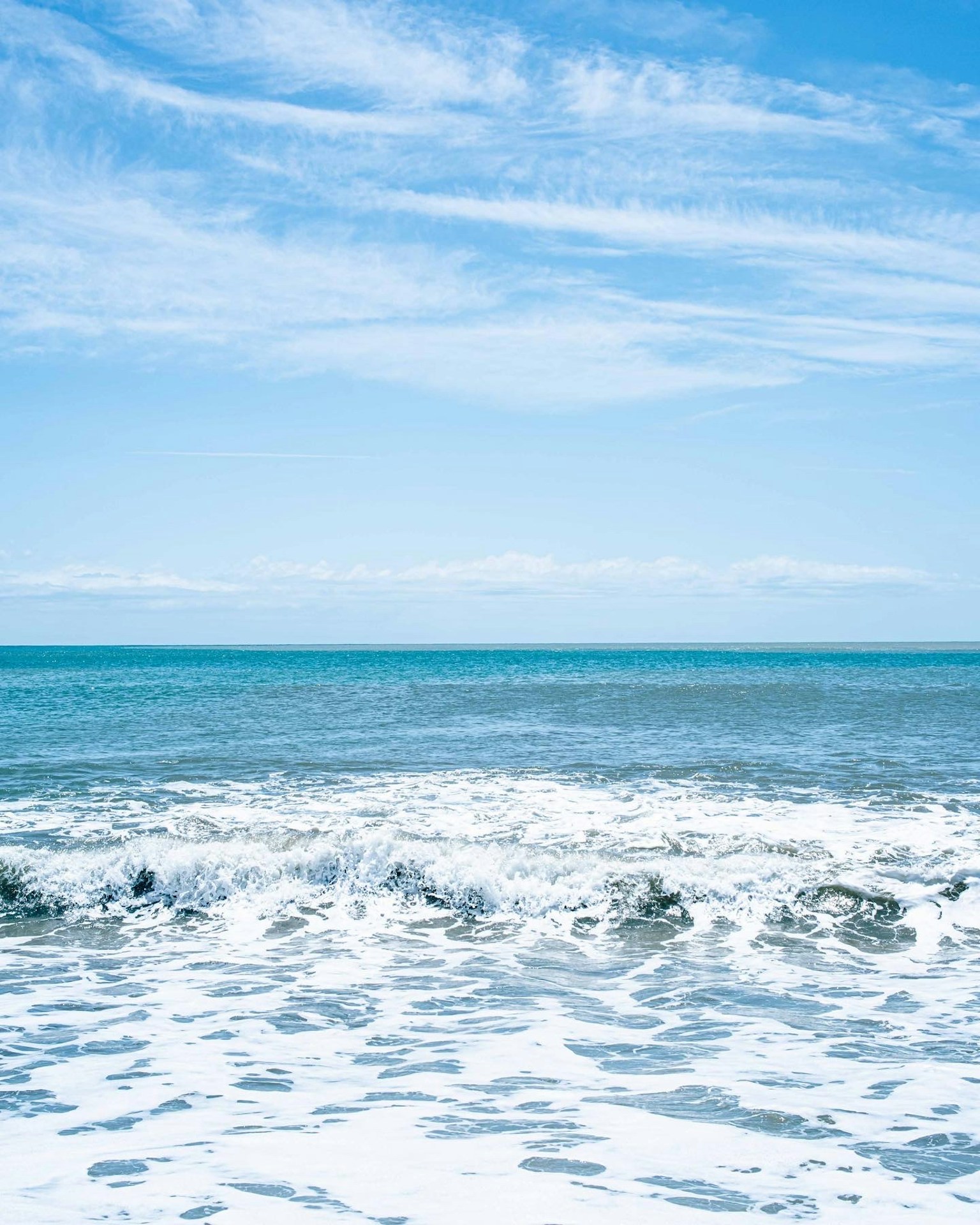Scenic view of blue ocean and white waves under a clear sky