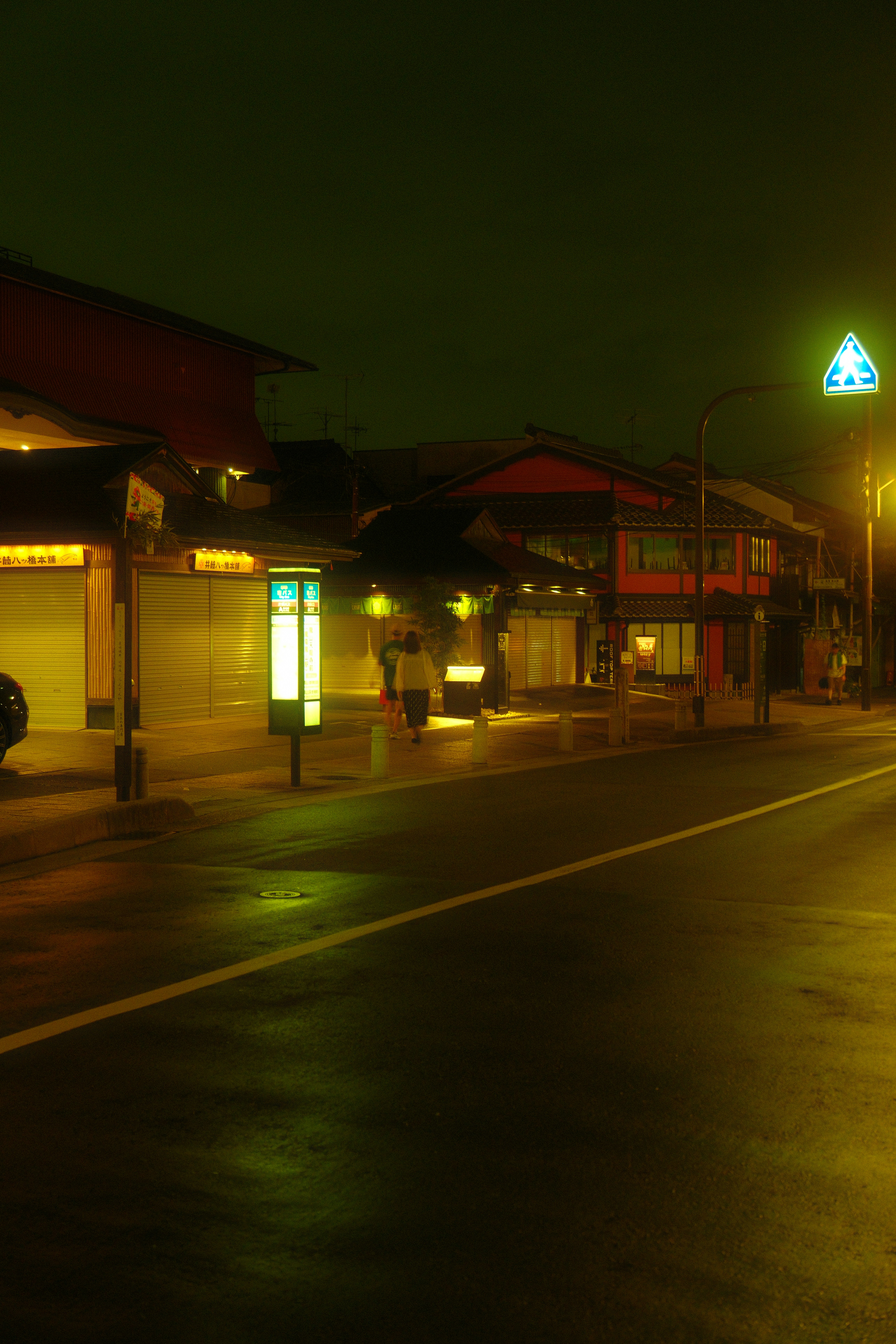 雨上がりの夜の商店街で足早に帰宅する人のスローシャッター