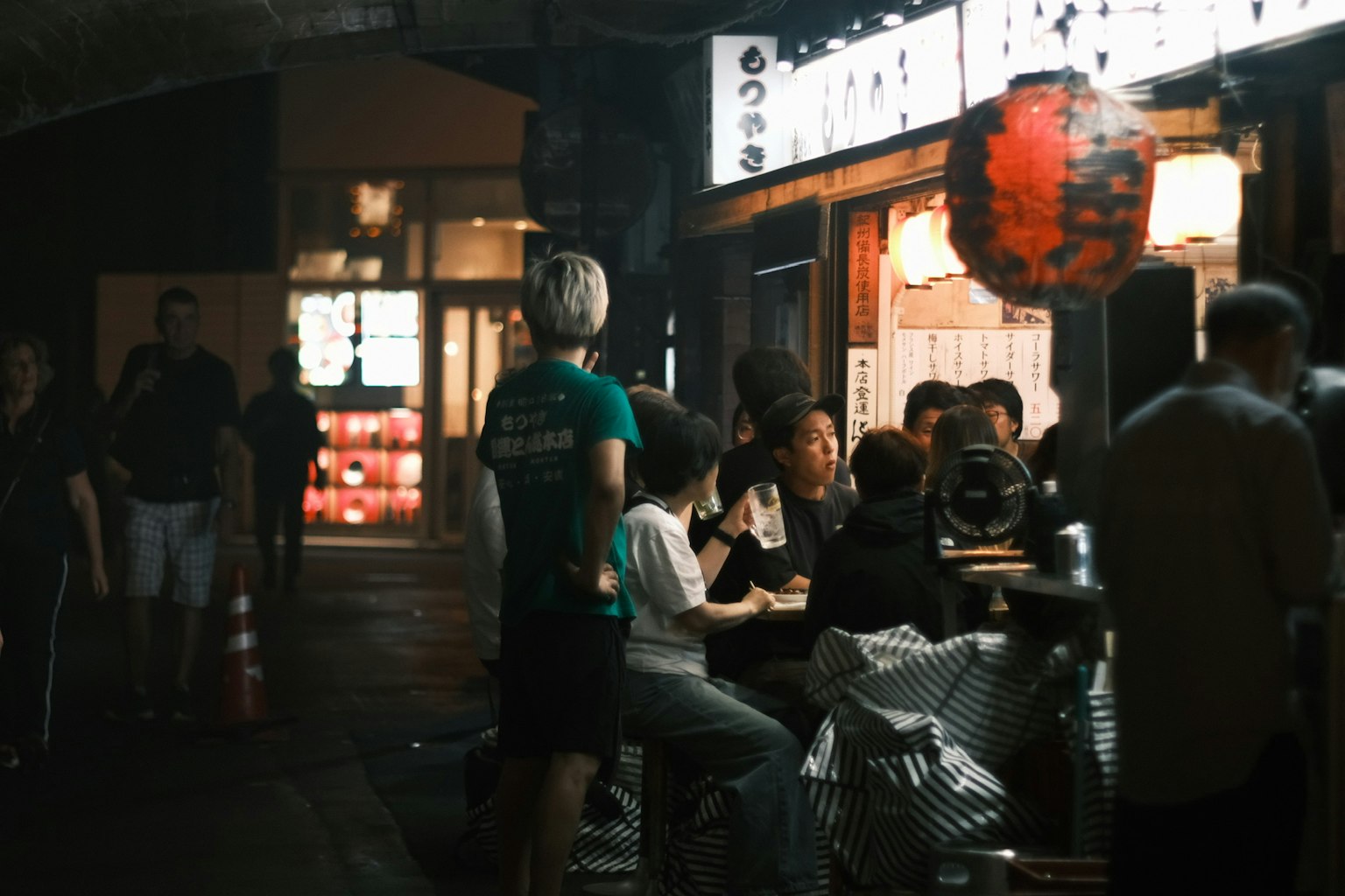 夜の屋台で食事を楽しむ人々と提灯の光