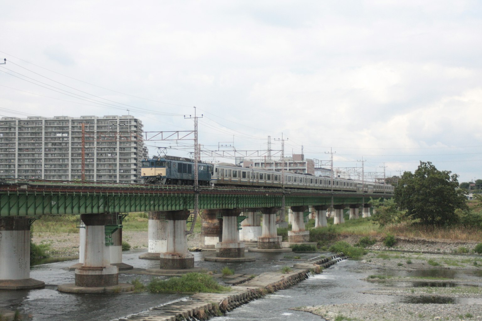 Train traversant une rivière avec des immeubles en arrière-plan