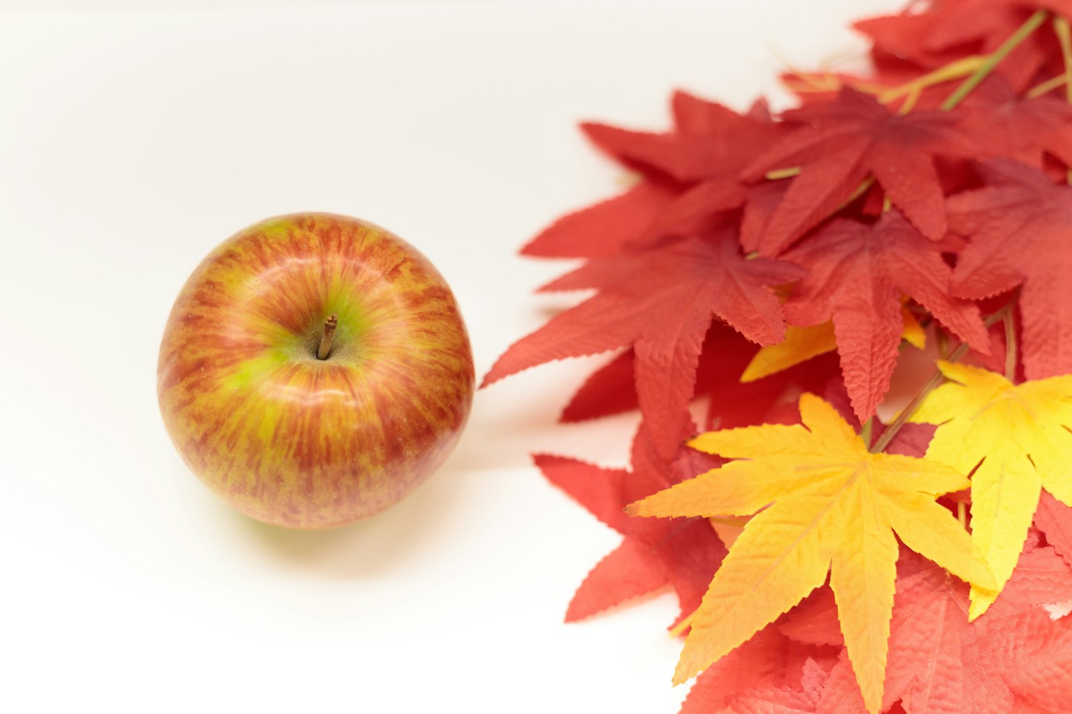 Une pomme à côté de feuilles d'automne rouges et jaunes