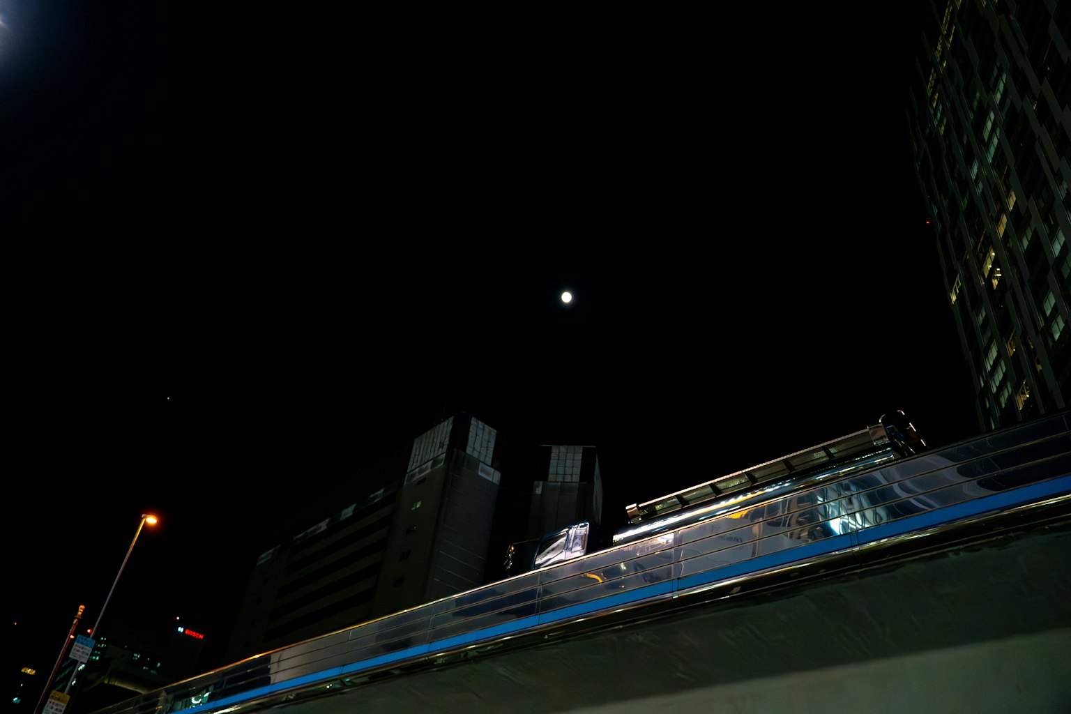 Mond sichtbar im Nachthimmel über Stadtgebäuden