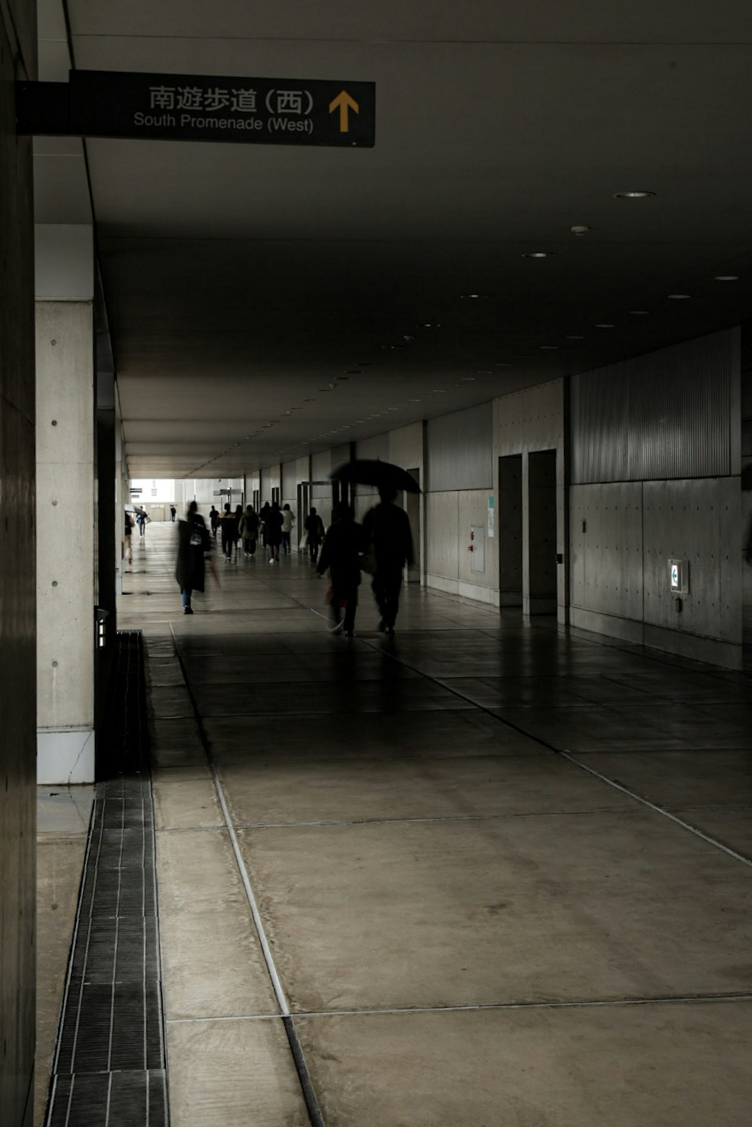 Des personnes marchant dans un couloir faiblement éclairé avec une ambiance calme
