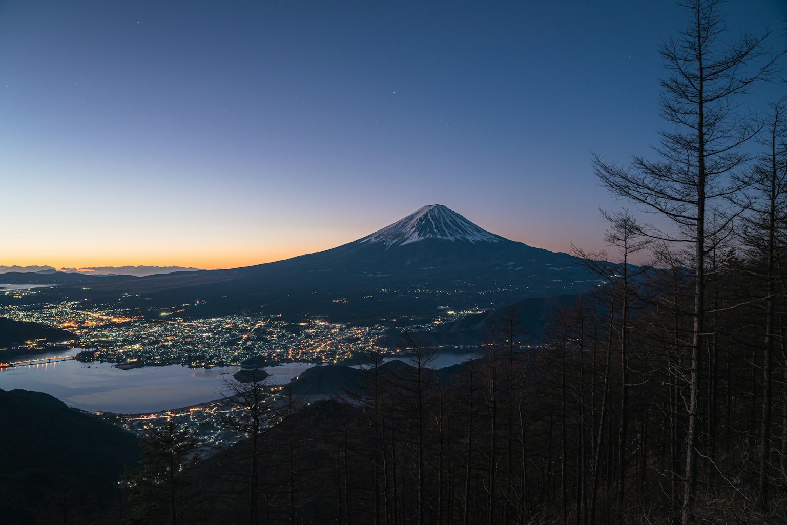 Impresionante vista del atardecer sobre el Monte Fuji con luces de la ciudad y el lago