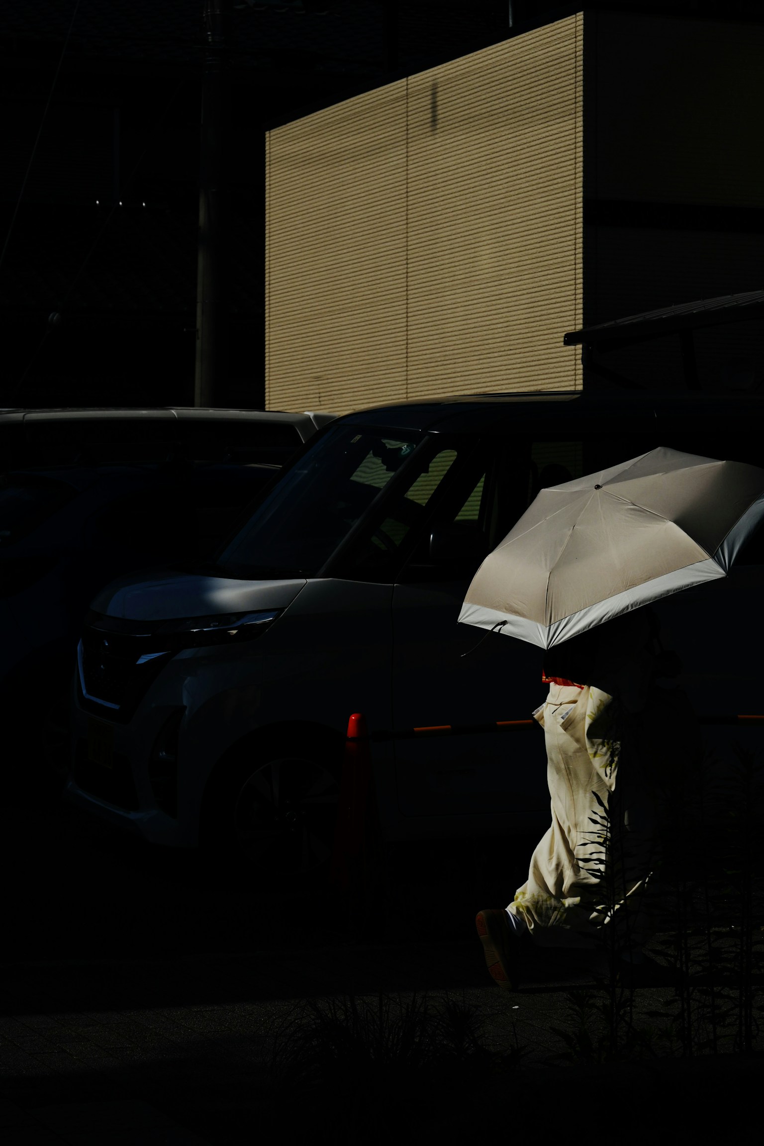 Una persona caminando con un paraguas en un fondo oscuro con coches