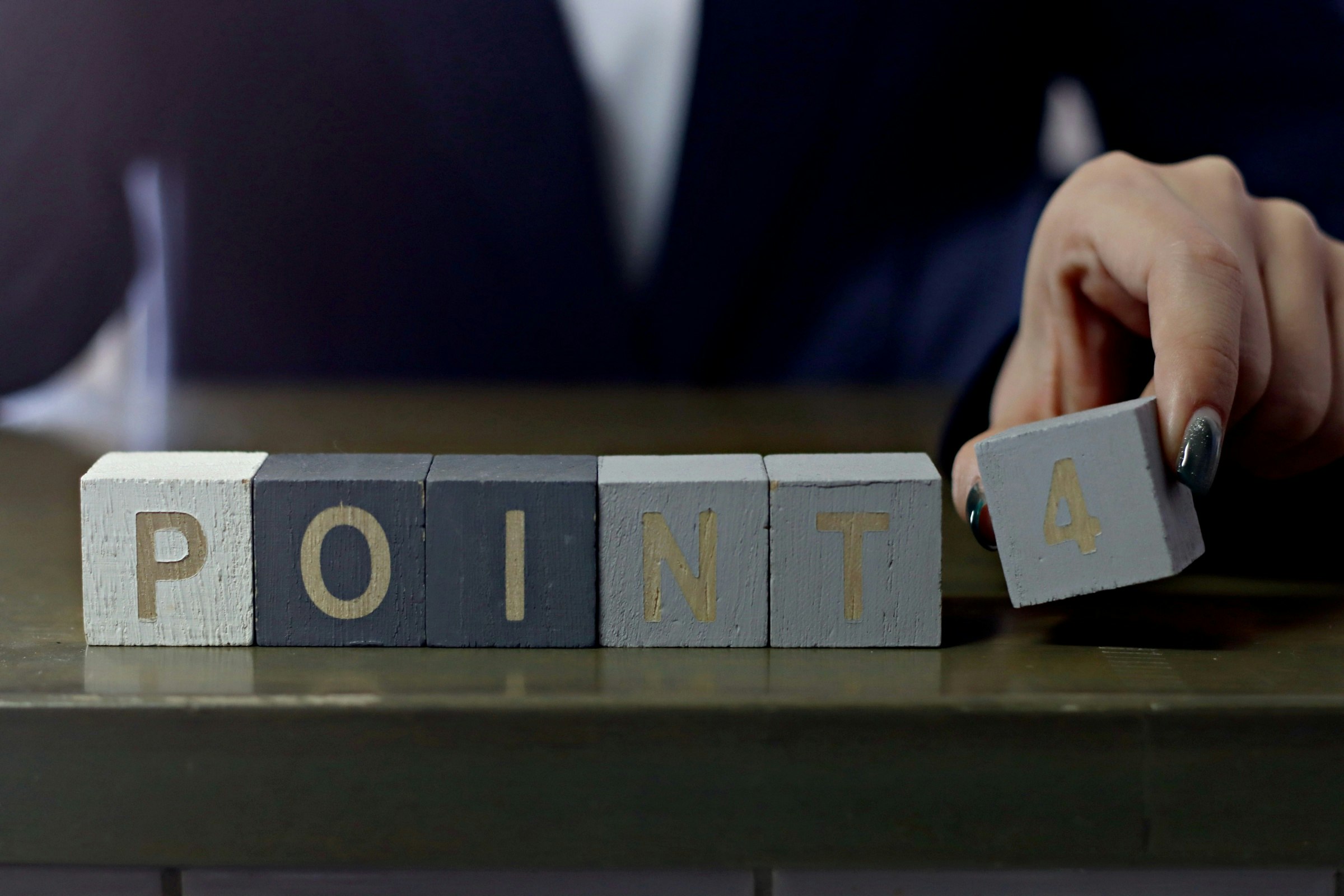 Business-Szene mit aufgestapelten Würfeln, die „POINT“ bilden, und einer Hand, die einen Würfel bewegt