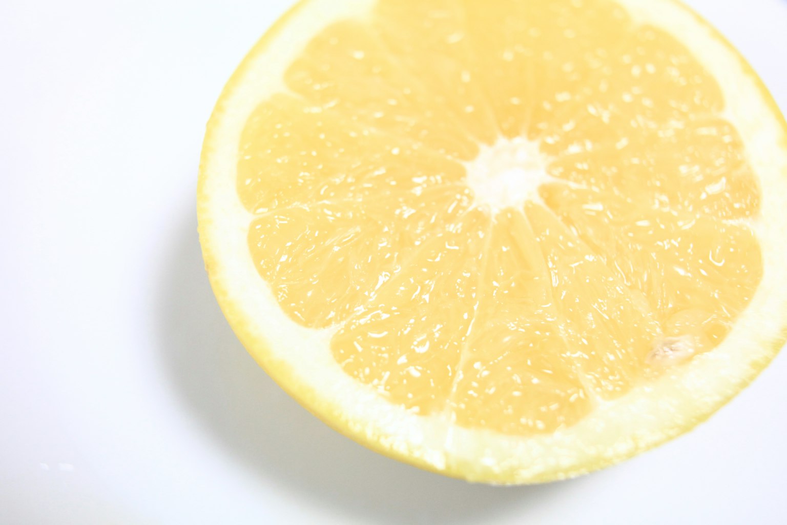 Un citron jaune coupé en deux sur une assiette blanche