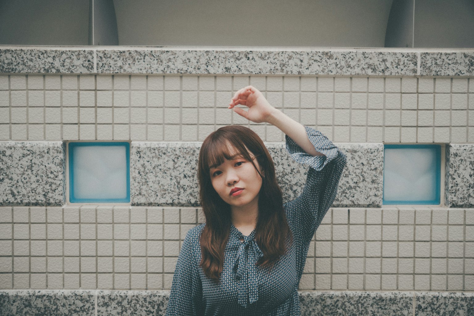 女性在瓷砖墙前举手的肖像