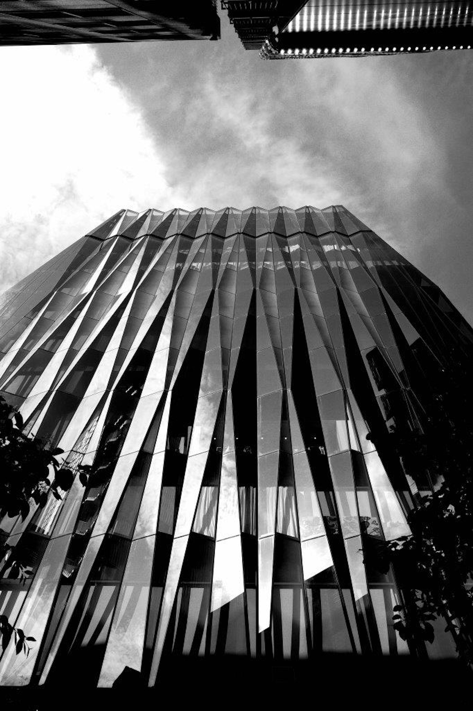 Vue d'un bâtiment moderne depuis le bas mettant en valeur sa façade en verre réfléchissant