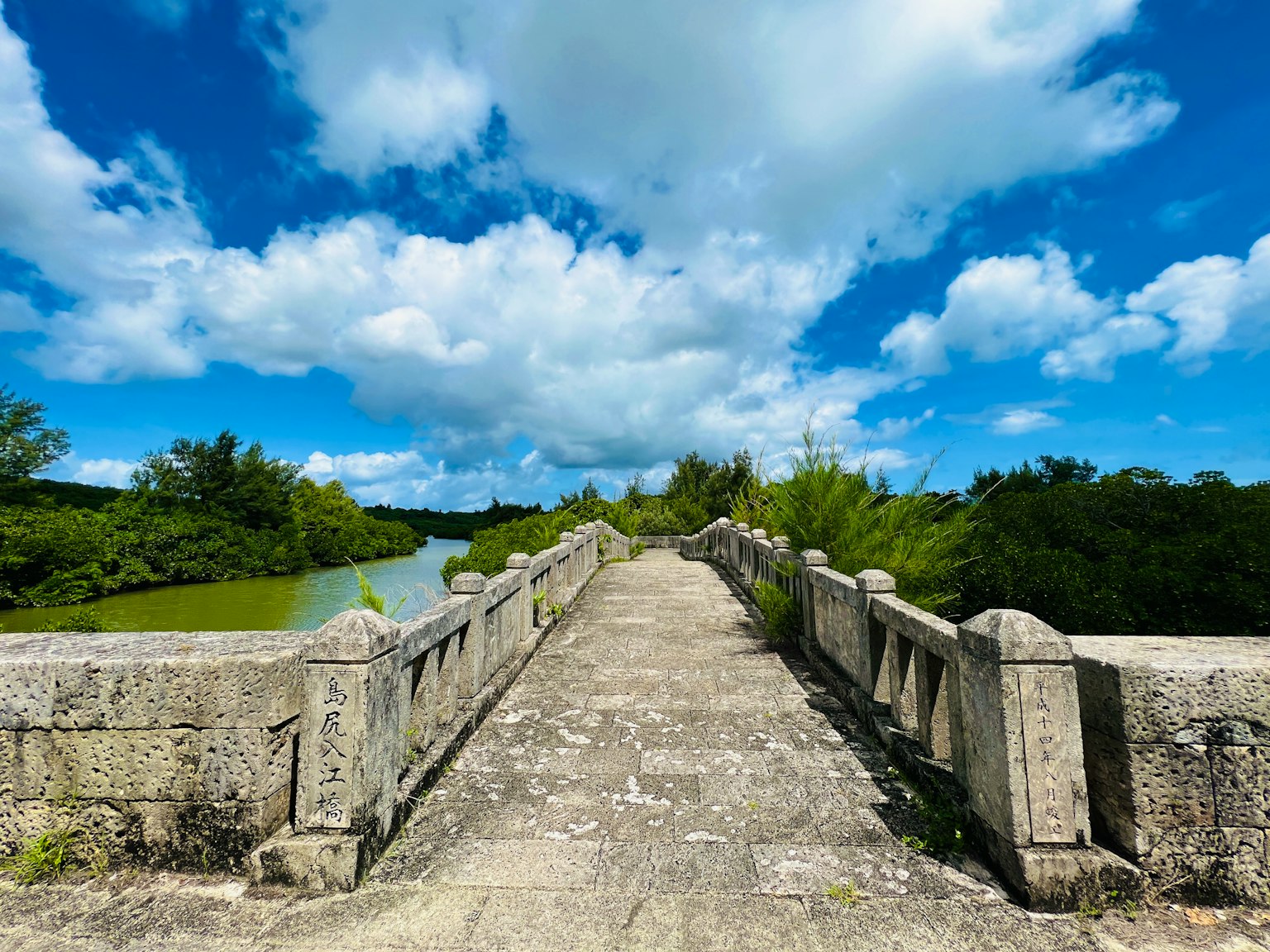 Alter Steinbrücke, die zu einer grünen Flusslandschaft führt