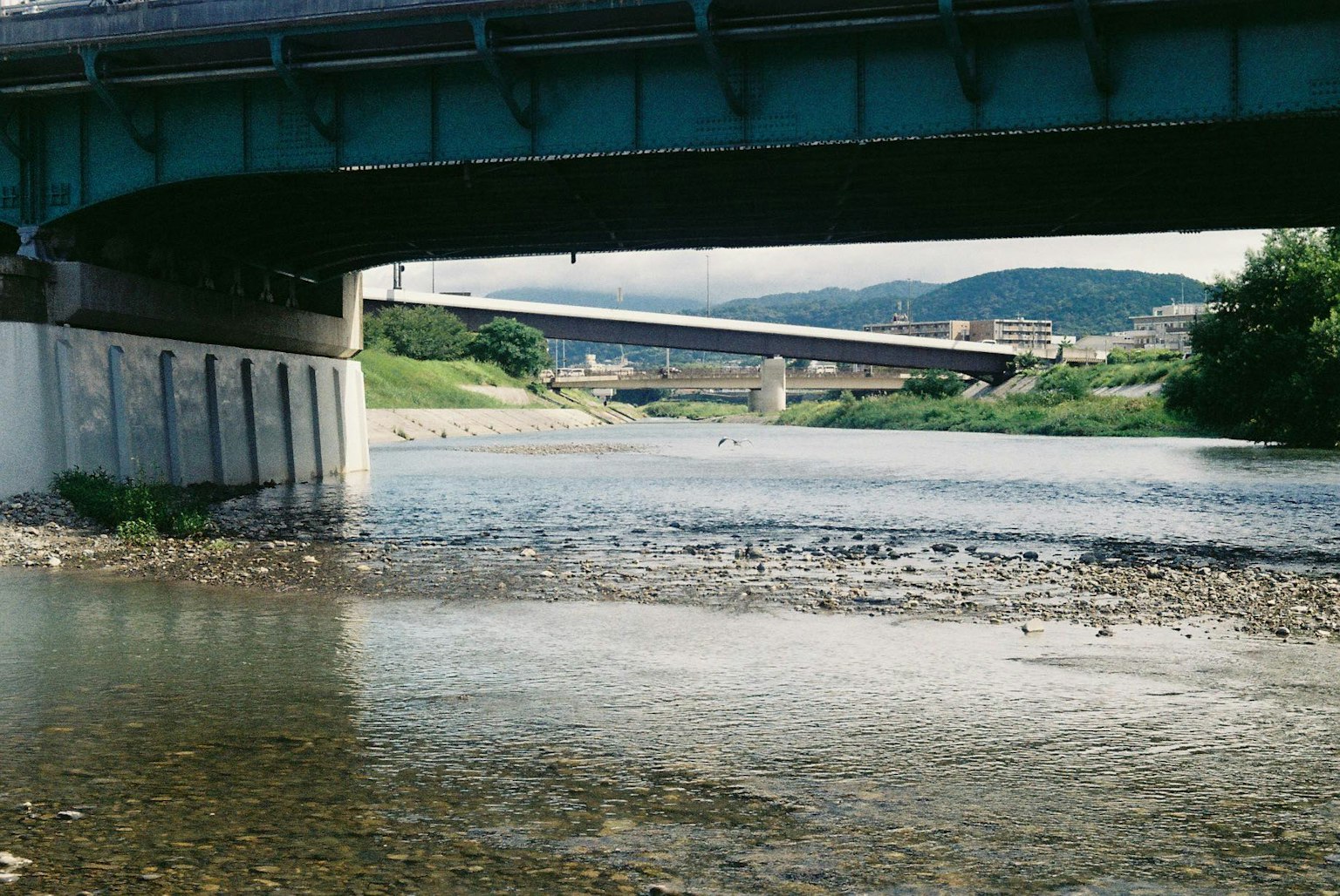 Vista de un puente azul sobre un río con otro puente a lo lejos