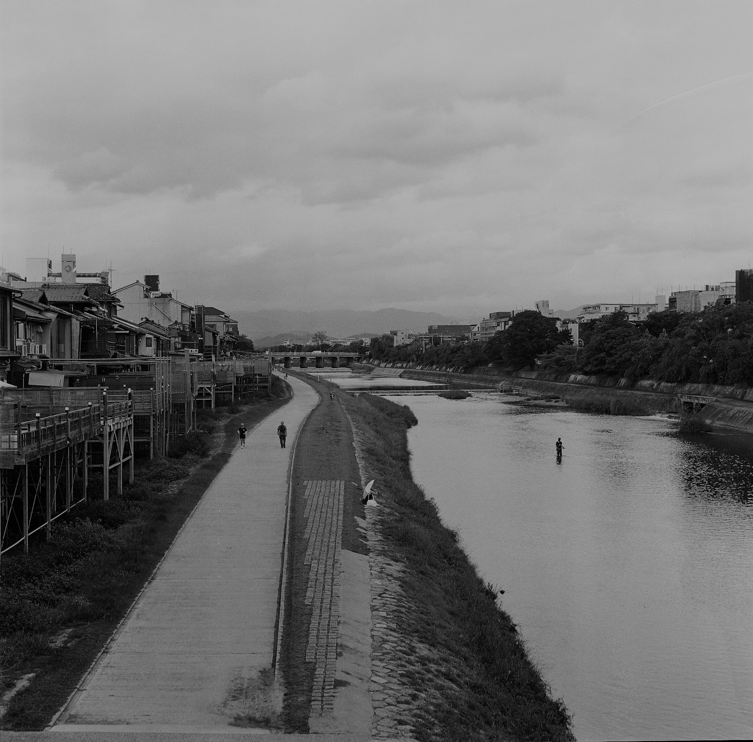 Scenic view of a riverbank with pathways and traditional buildings