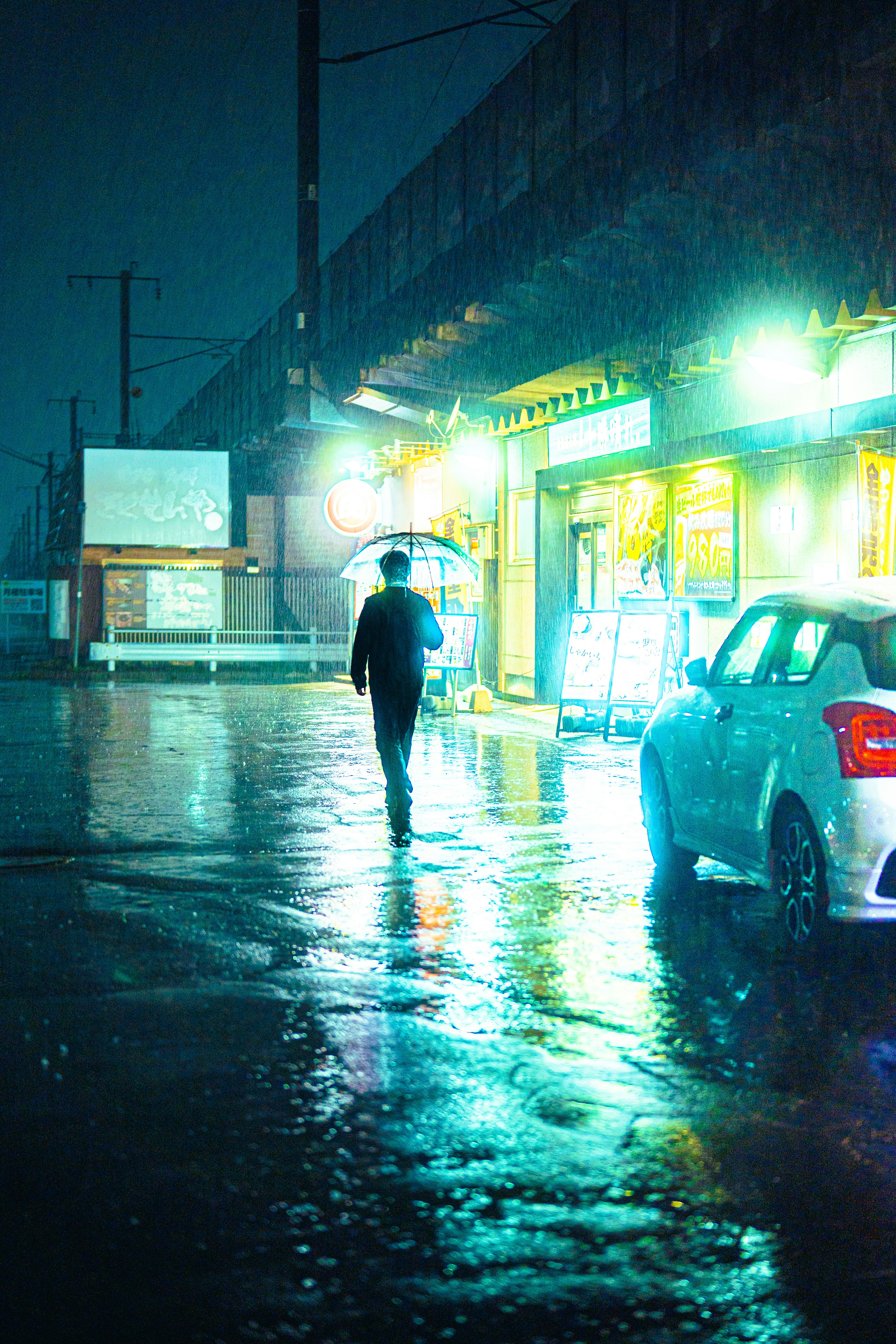 雨の夜の街角で光る屋台の看板と歩く人