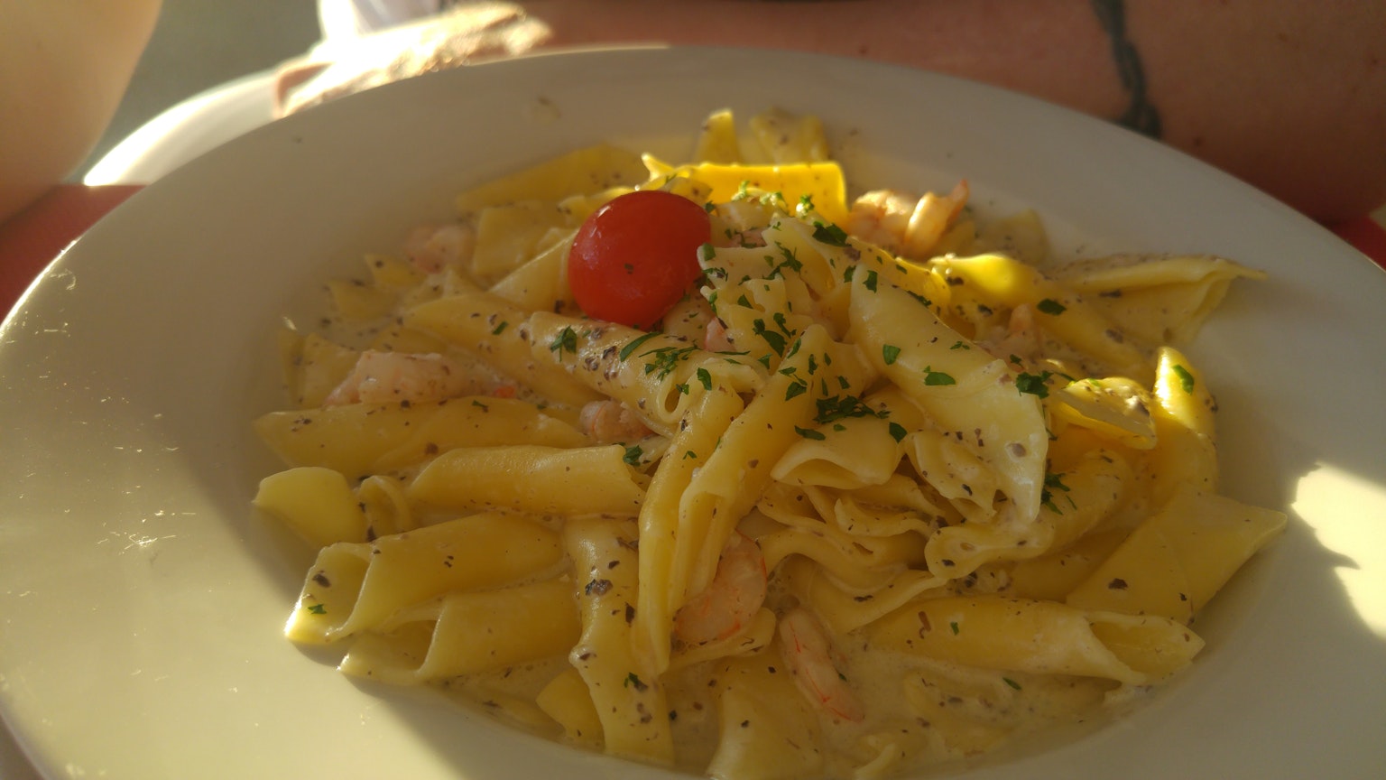 Plate of pasta with creamy sauce and topped with cherry tomato