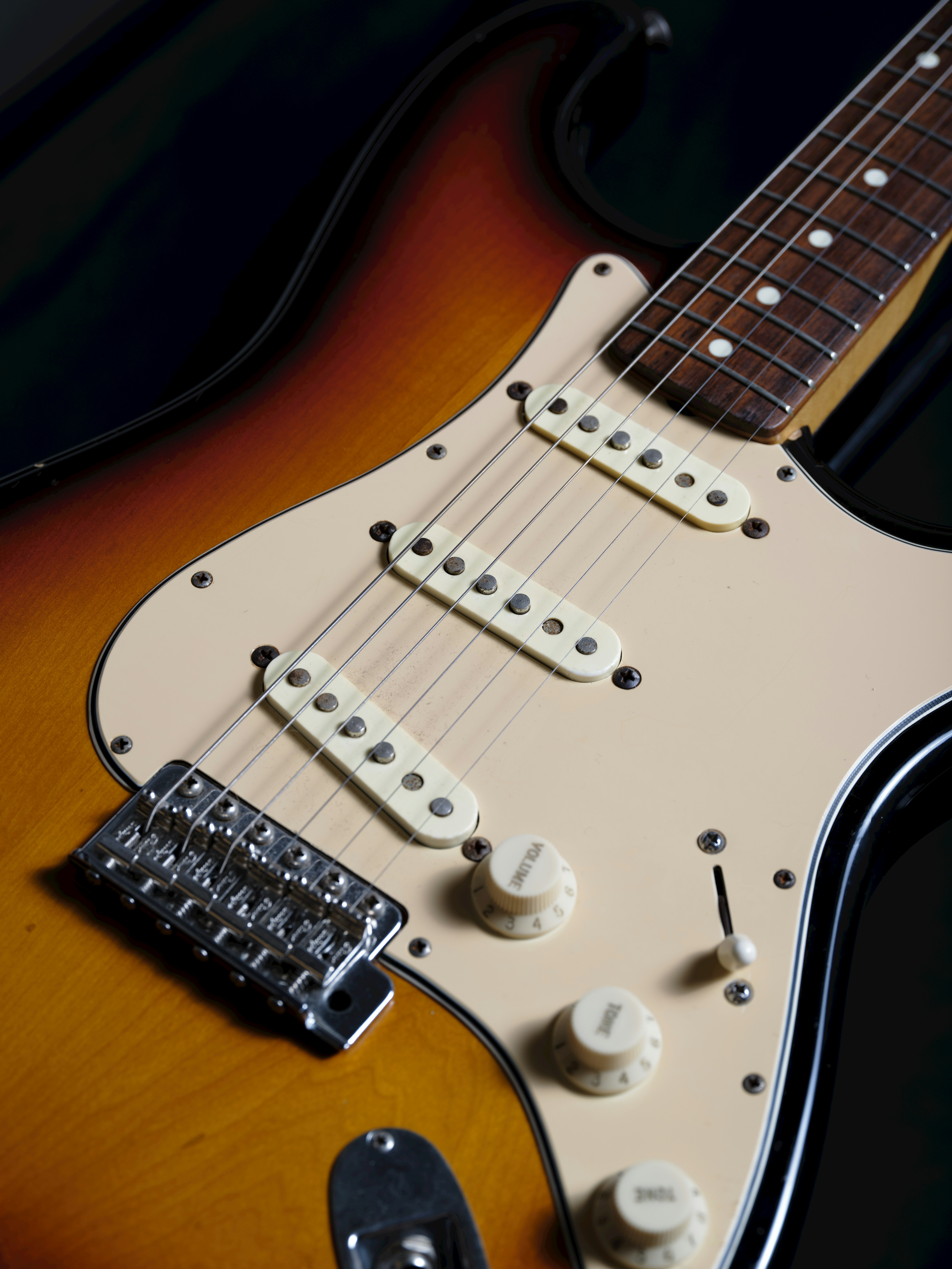 Kamera dekat gitar listrik dengan finishing sunburst dan pickup berwarna krim