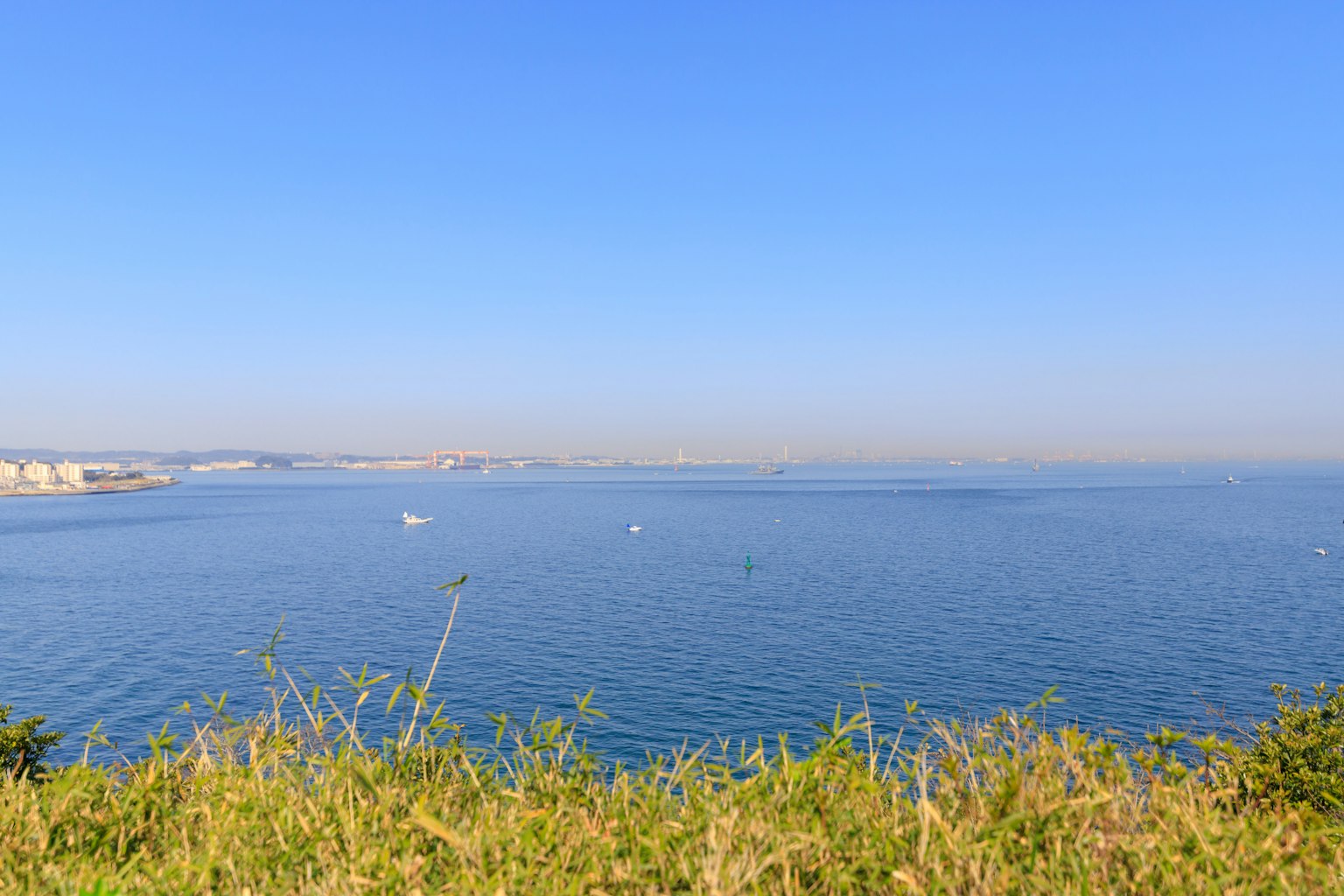 Malersicher Blick auf das blaue Meer und den Himmel von einem grasbewachsenen Hügel