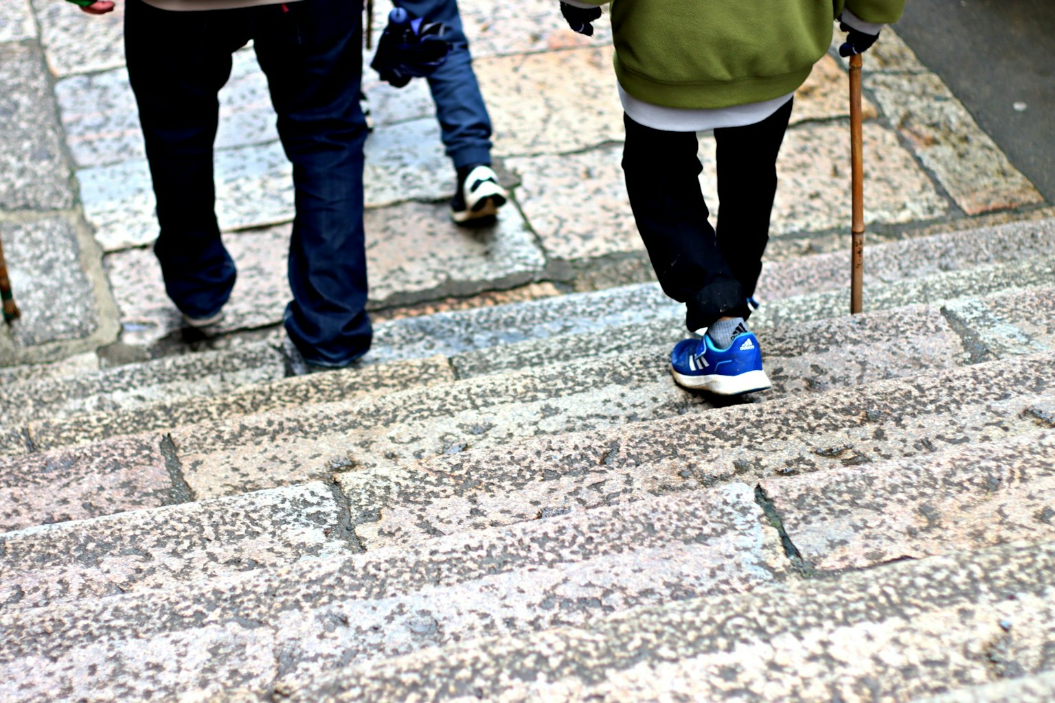 Kinder gehen eine Steintreppe hinunter mit Marmorstufen und Turnschuhen