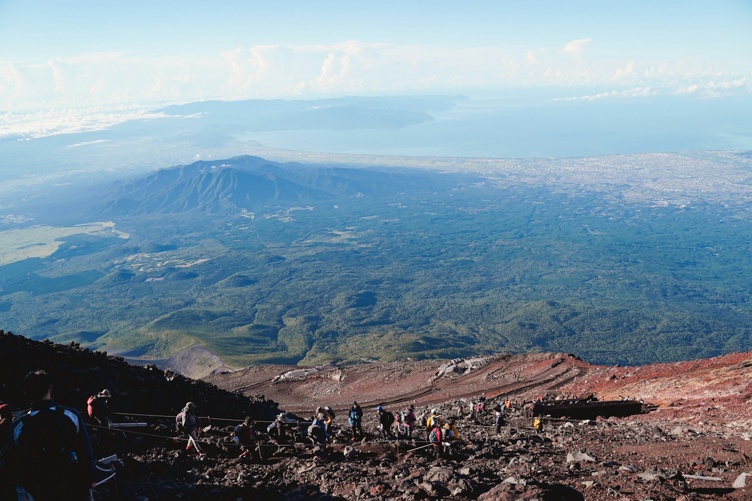 Randonneurs montant une pente volcanique avec vue panoramique