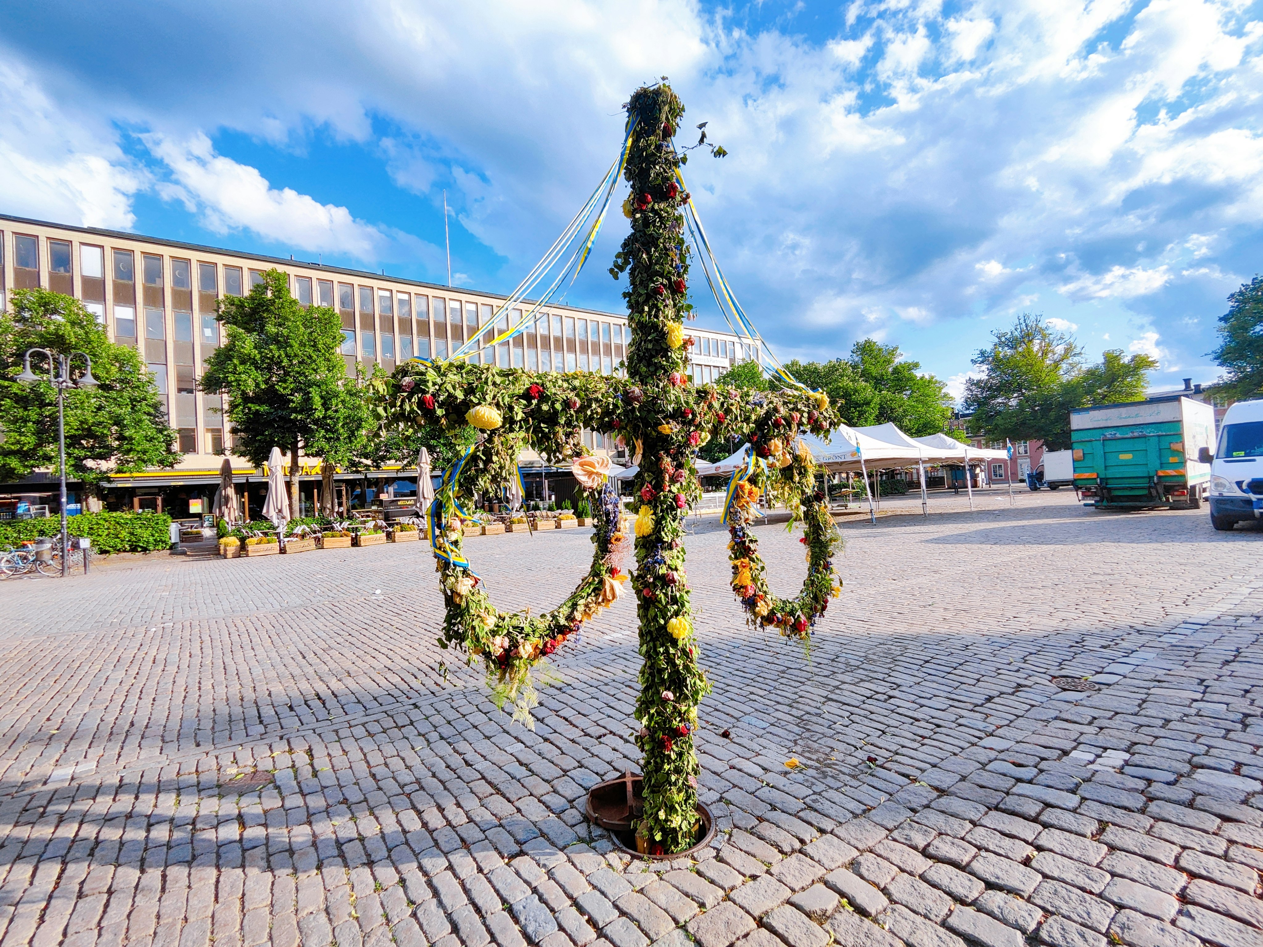 Outdoor-Event auf einem Platz mit hängender Blumenskulptur und Zelten