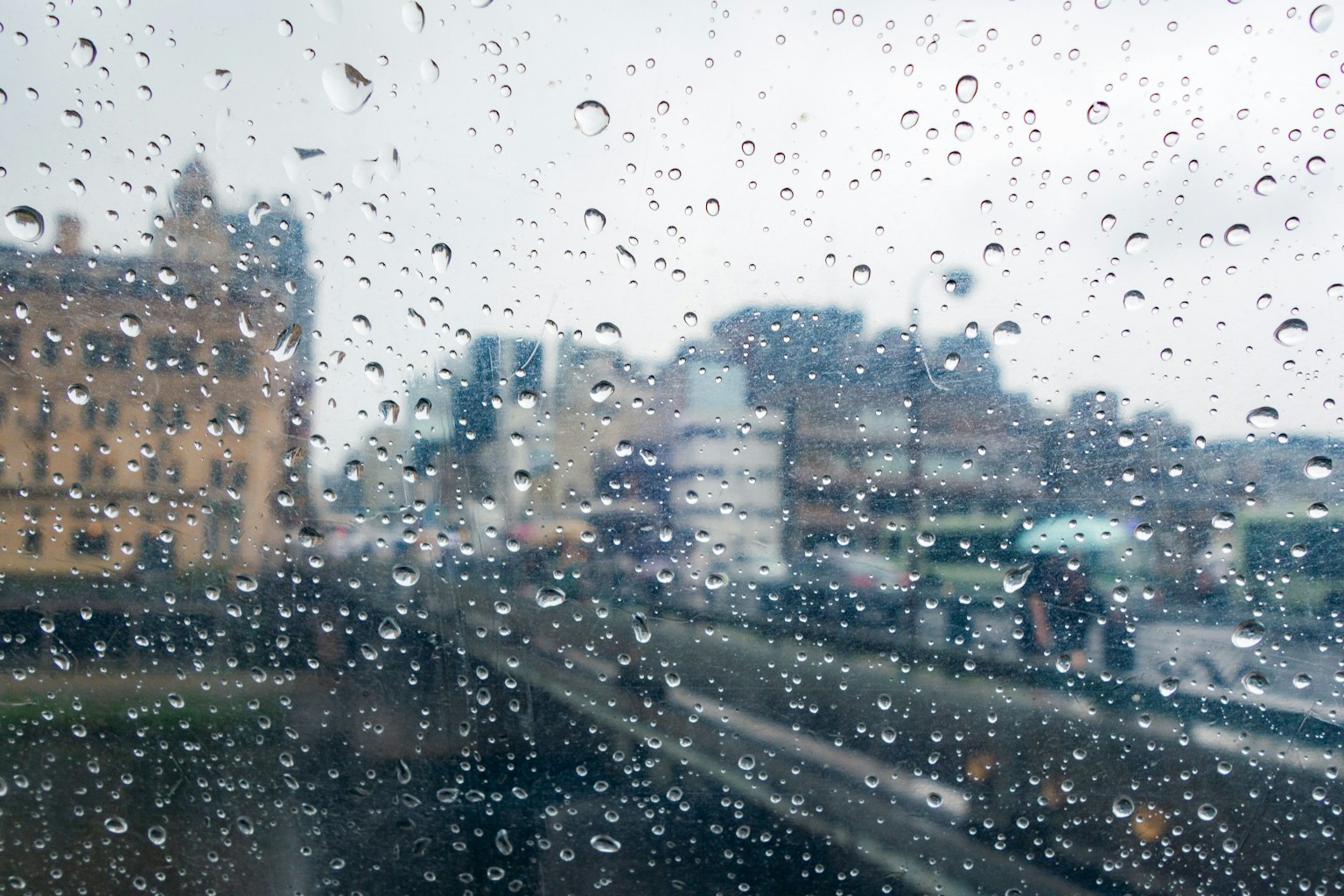 Paisaje urbano visto a través de una ventana empapada de lluvia personas con paraguas